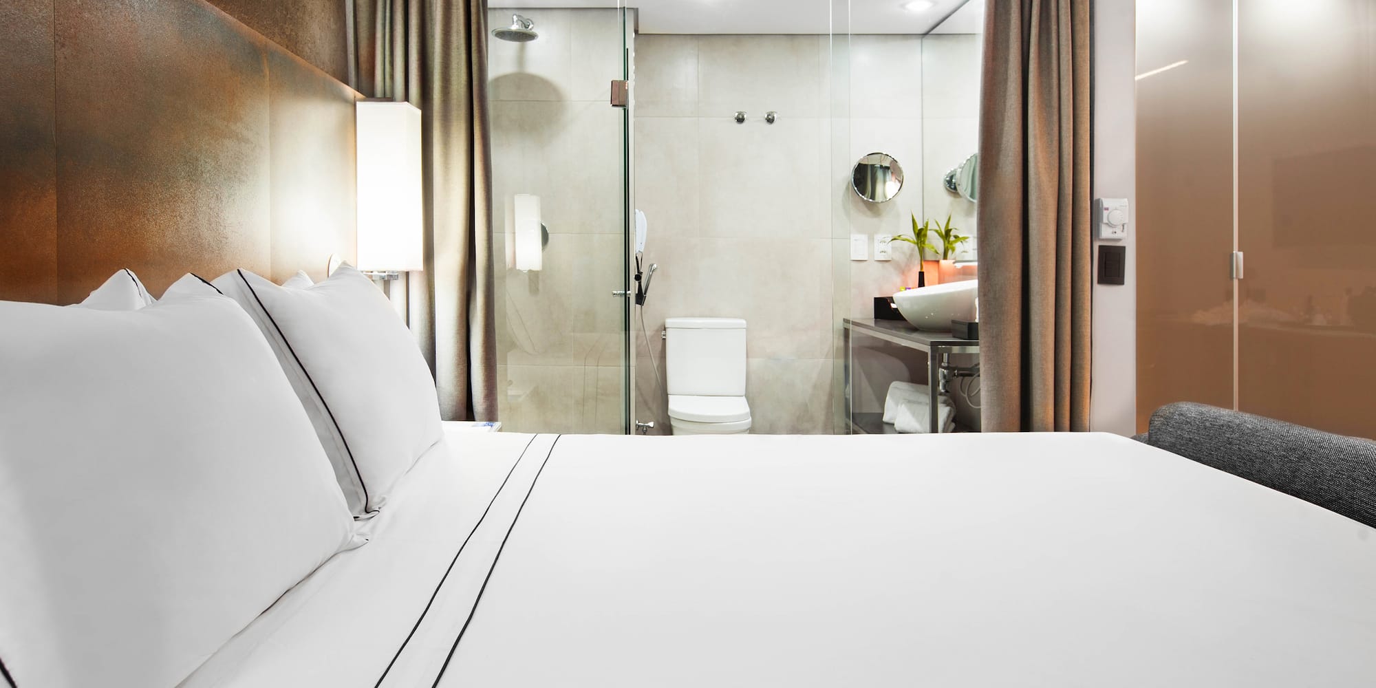 a bed with white sheets and a glass shower door