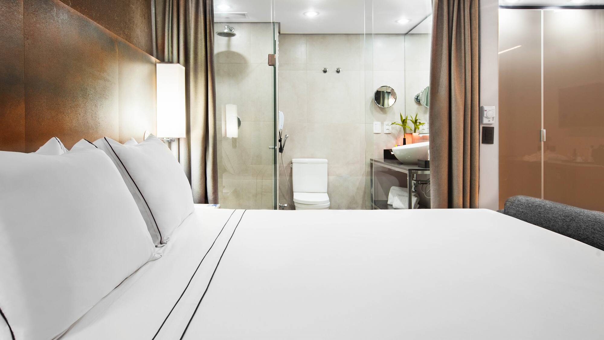 a bed with white sheets and a glass shower door