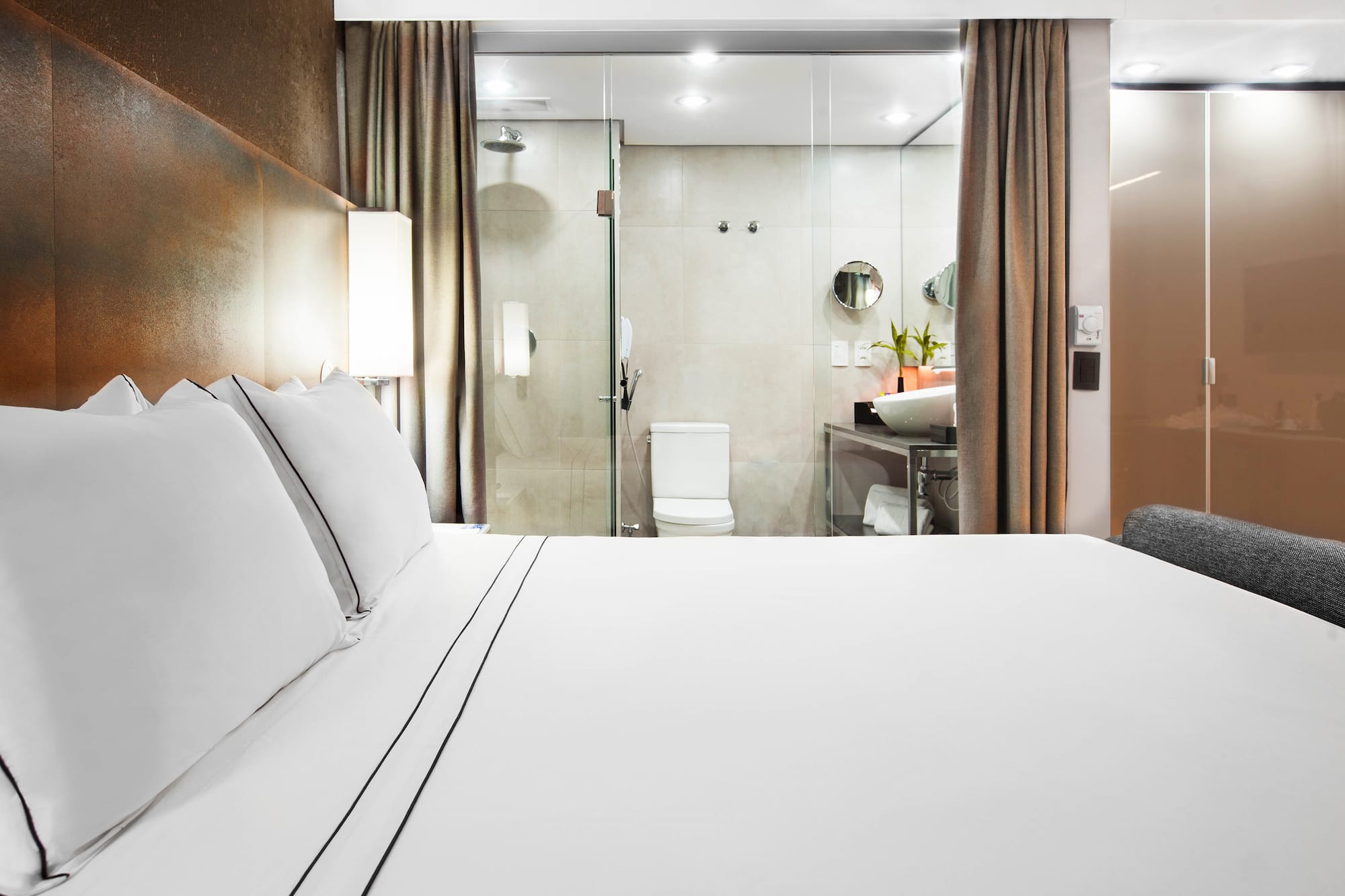 a bed with white sheets and a glass shower door