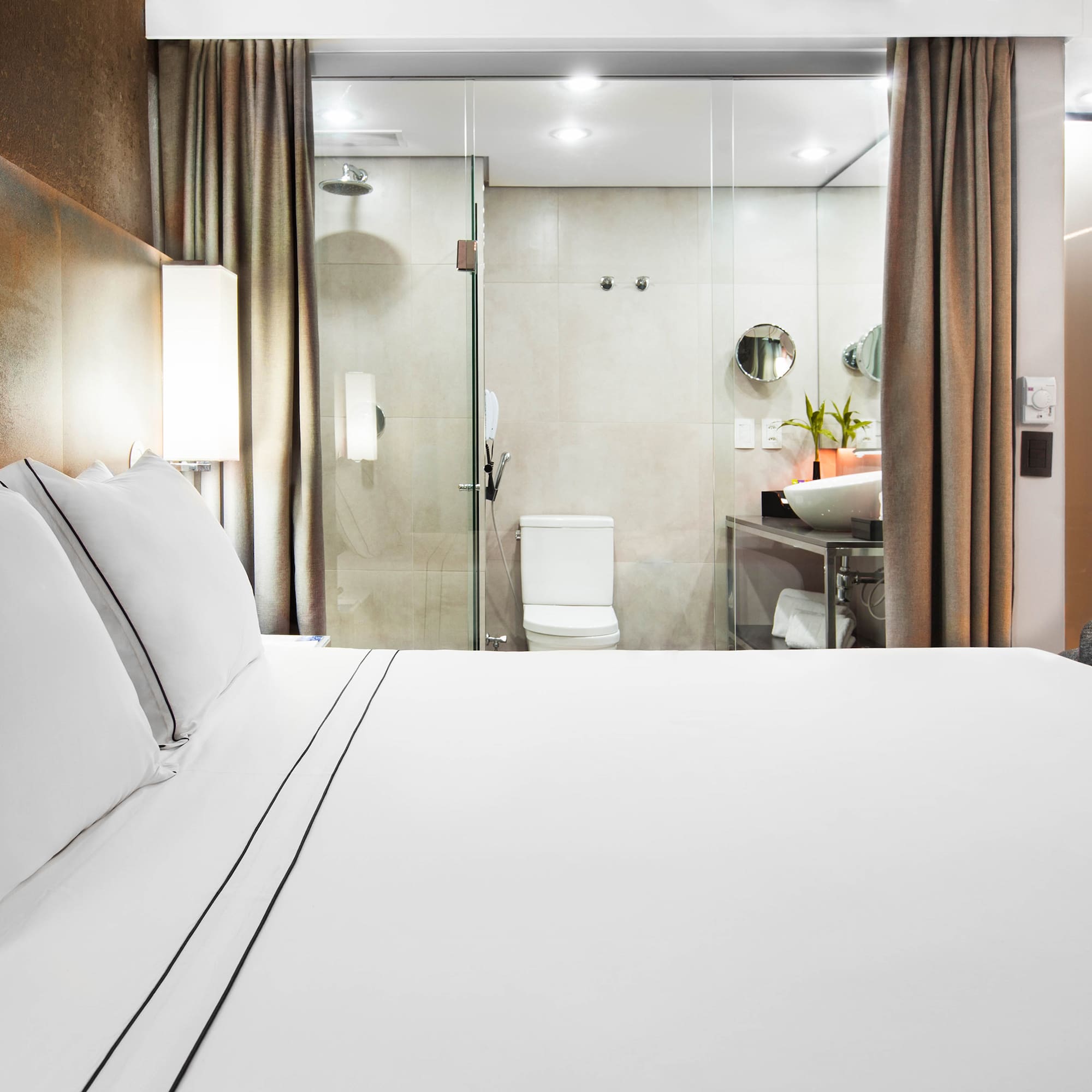 a bed with white sheets and a glass shower door