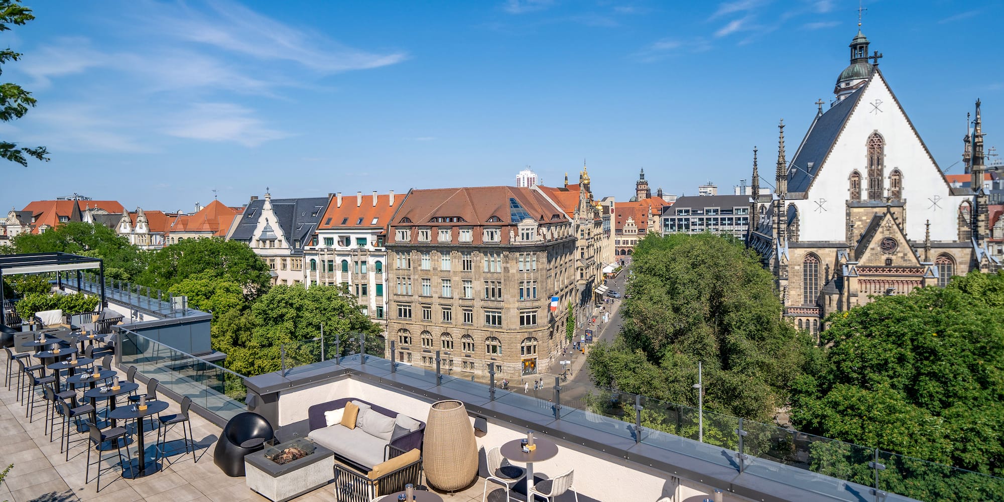 a rooftop patio with tables and chairs and trees