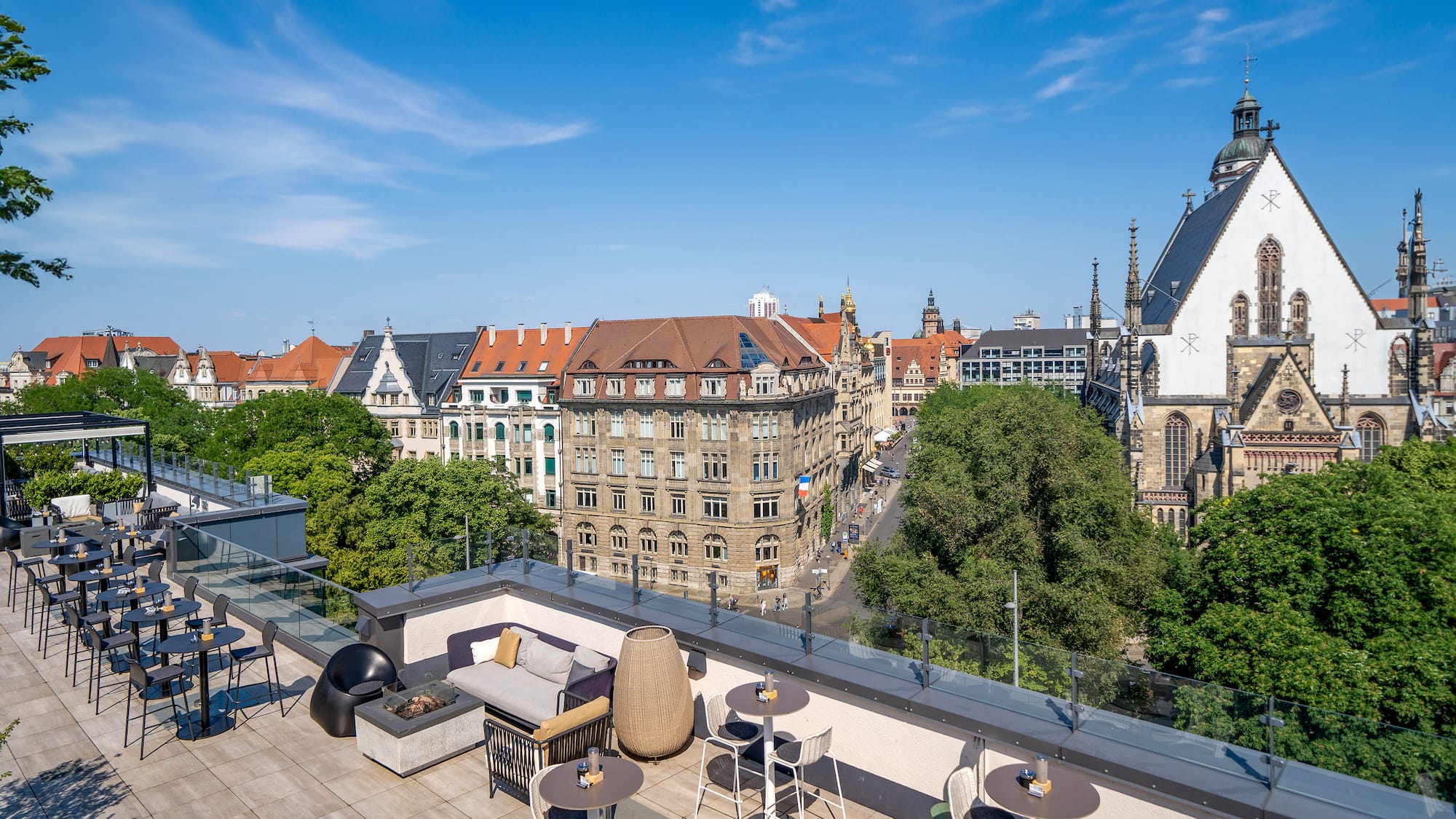 a rooftop patio with tables and chairs and trees