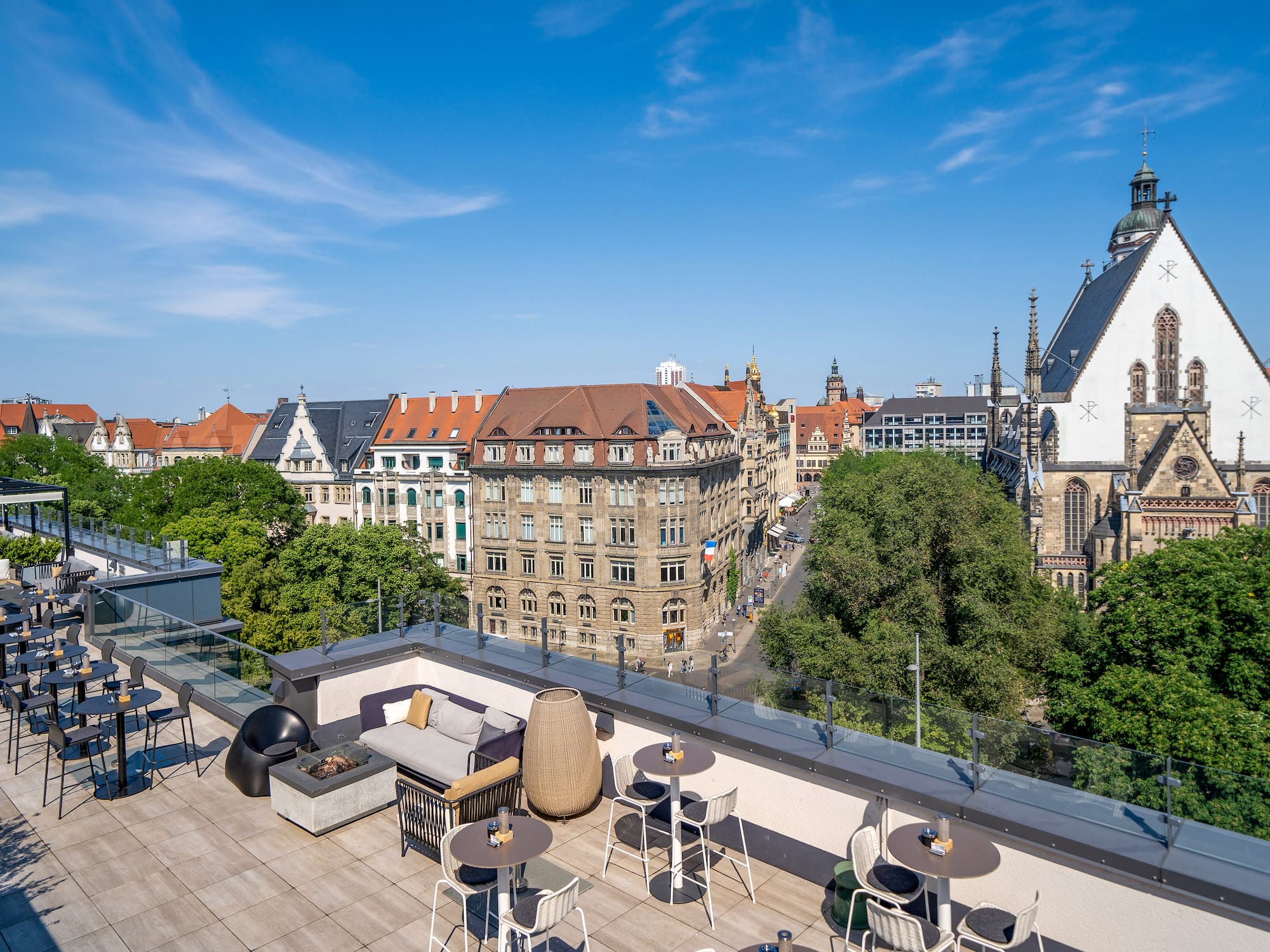 Leipzig rooftop bar with city skyline and St. Thomas Church view.