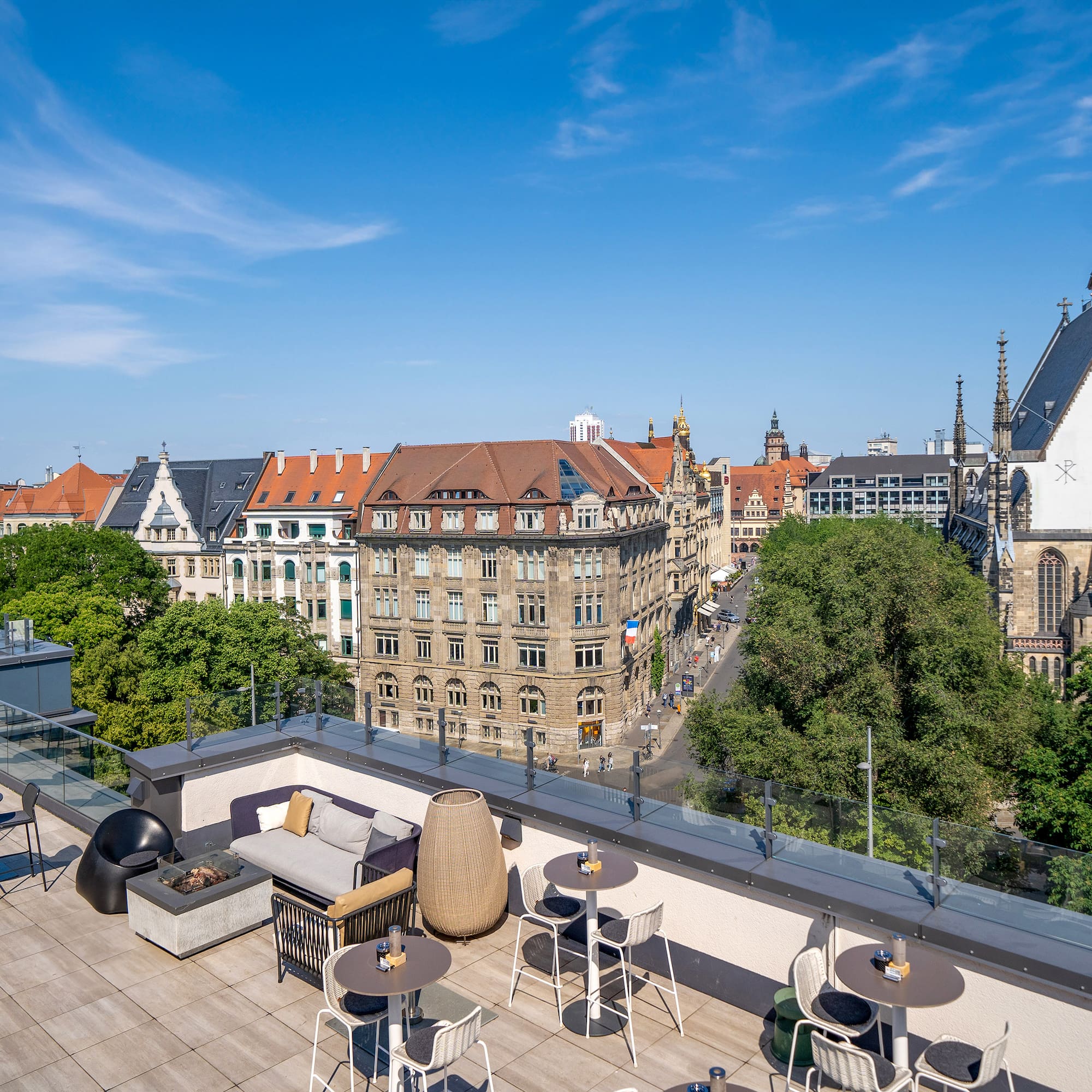 a rooftop patio with tables and chairs and trees