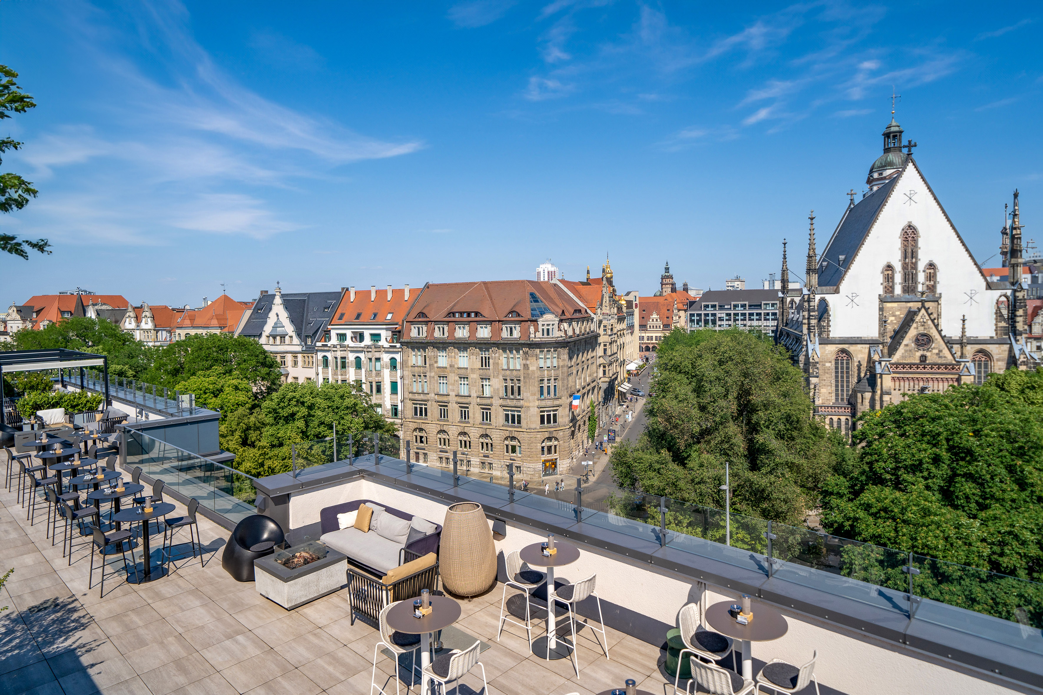a rooftop patio with tables and chairs and trees