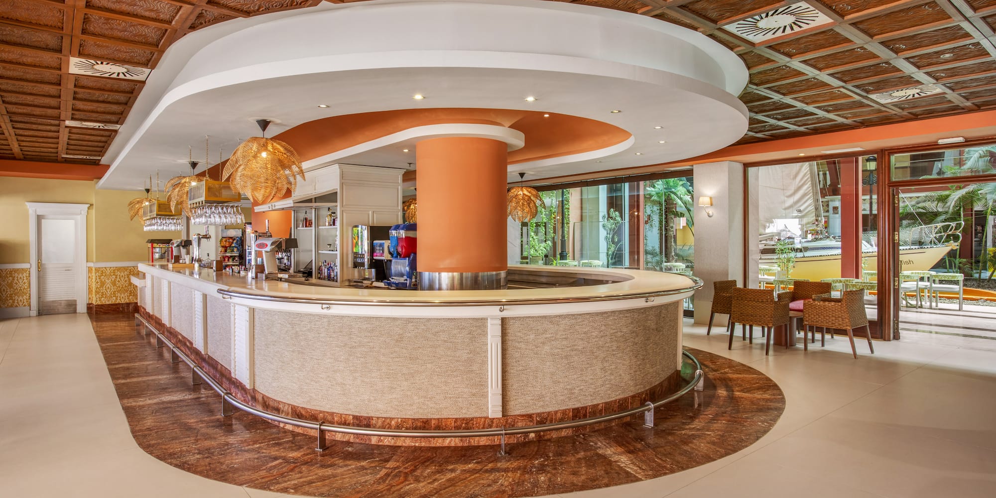 Lush hotel lobby bar with carved ceiling, modern counter, and tropical patio.