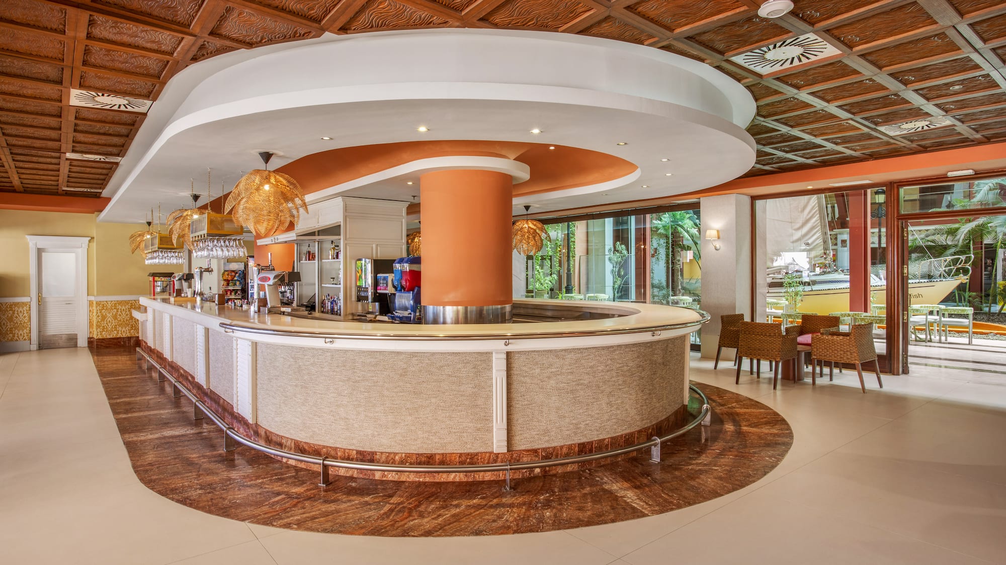 Lush hotel lobby bar with carved ceiling, modern counter, and tropical patio.