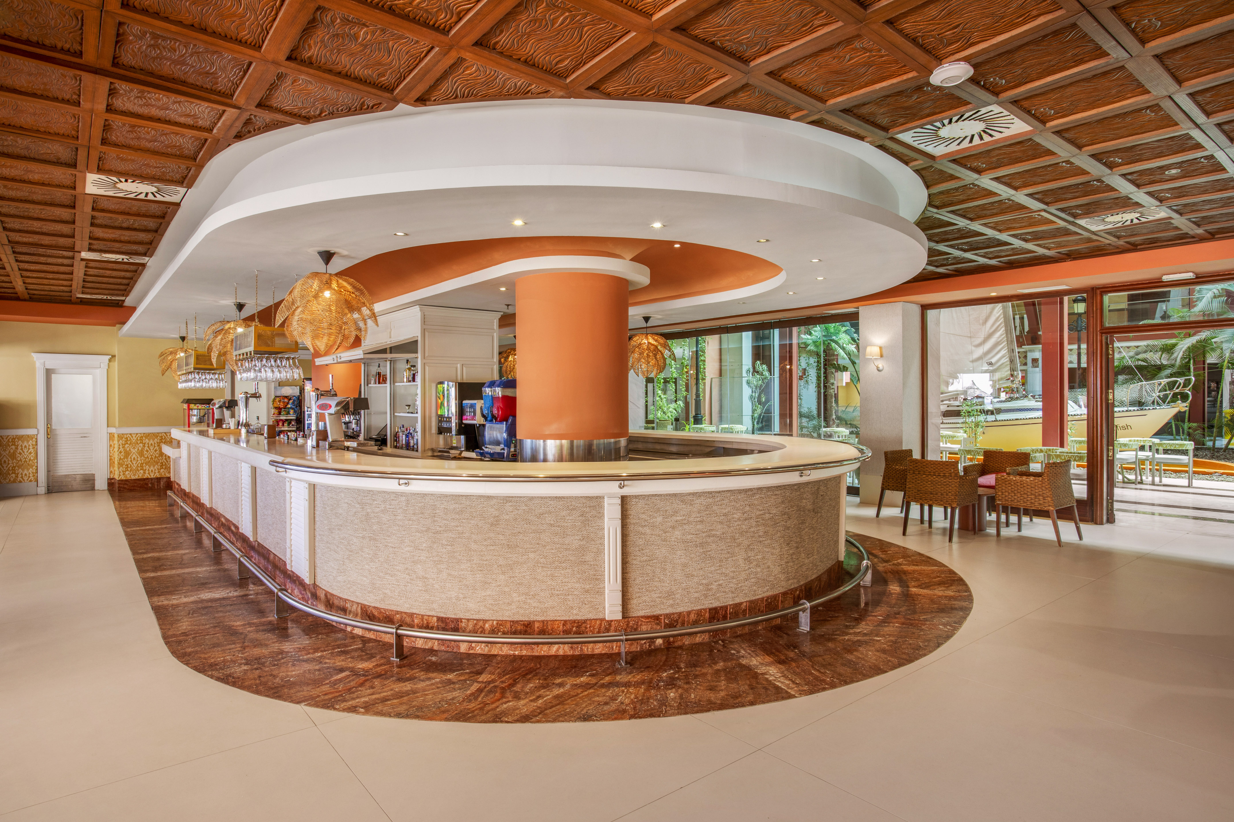 Lush hotel lobby bar with carved ceiling, modern counter, and tropical patio.