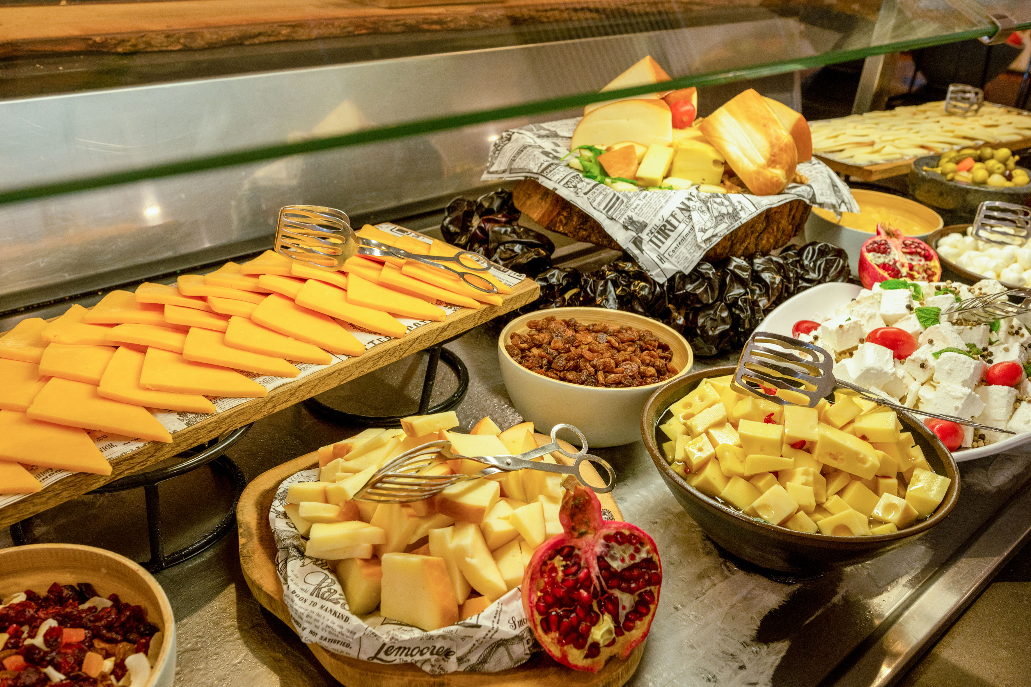 Gourmet cheese buffet featuring various cheeses, dried fruits, olives, and pomegranate.
