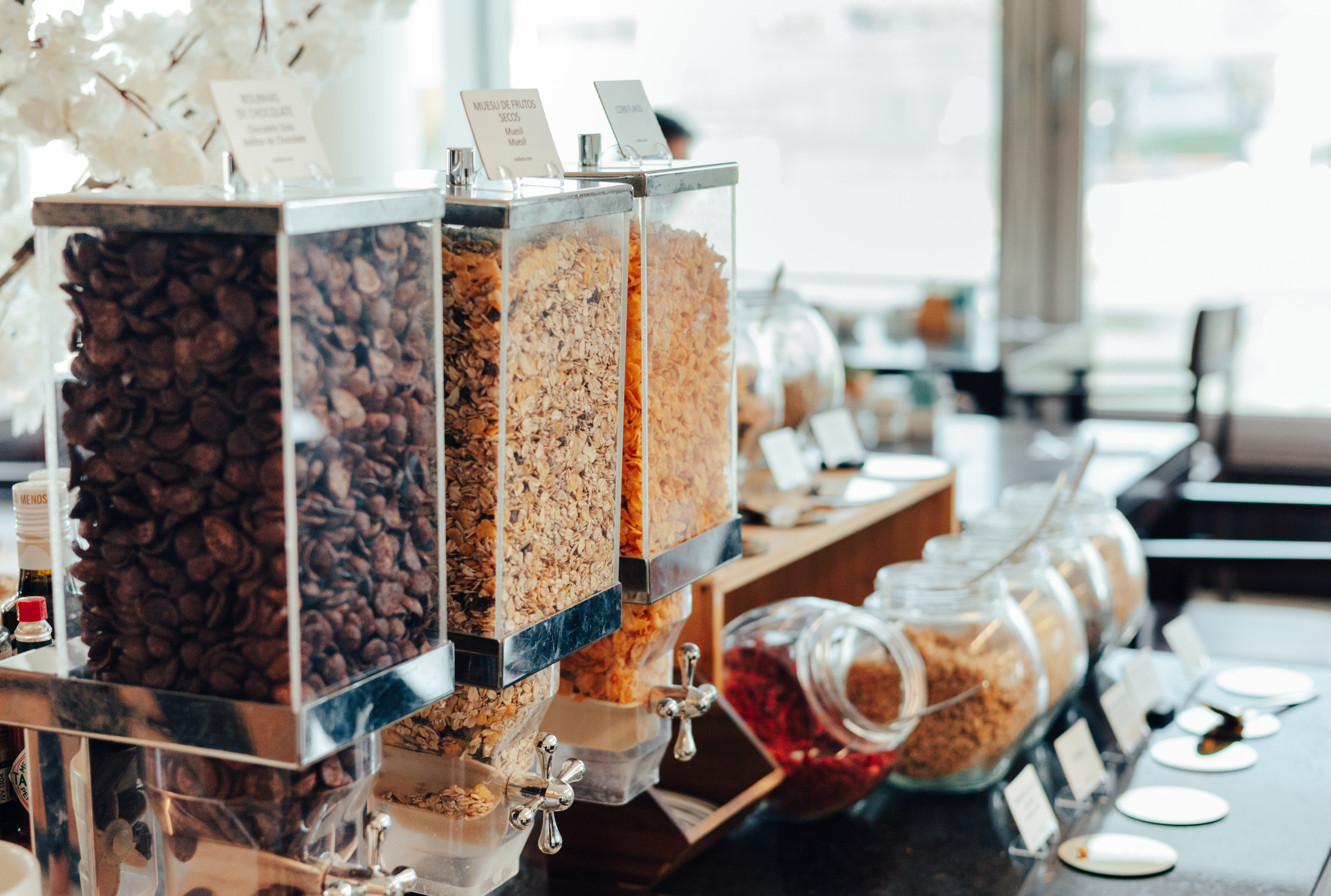Breakfast buffet with chocolate, muesli, and cornflake cereal dispensers.