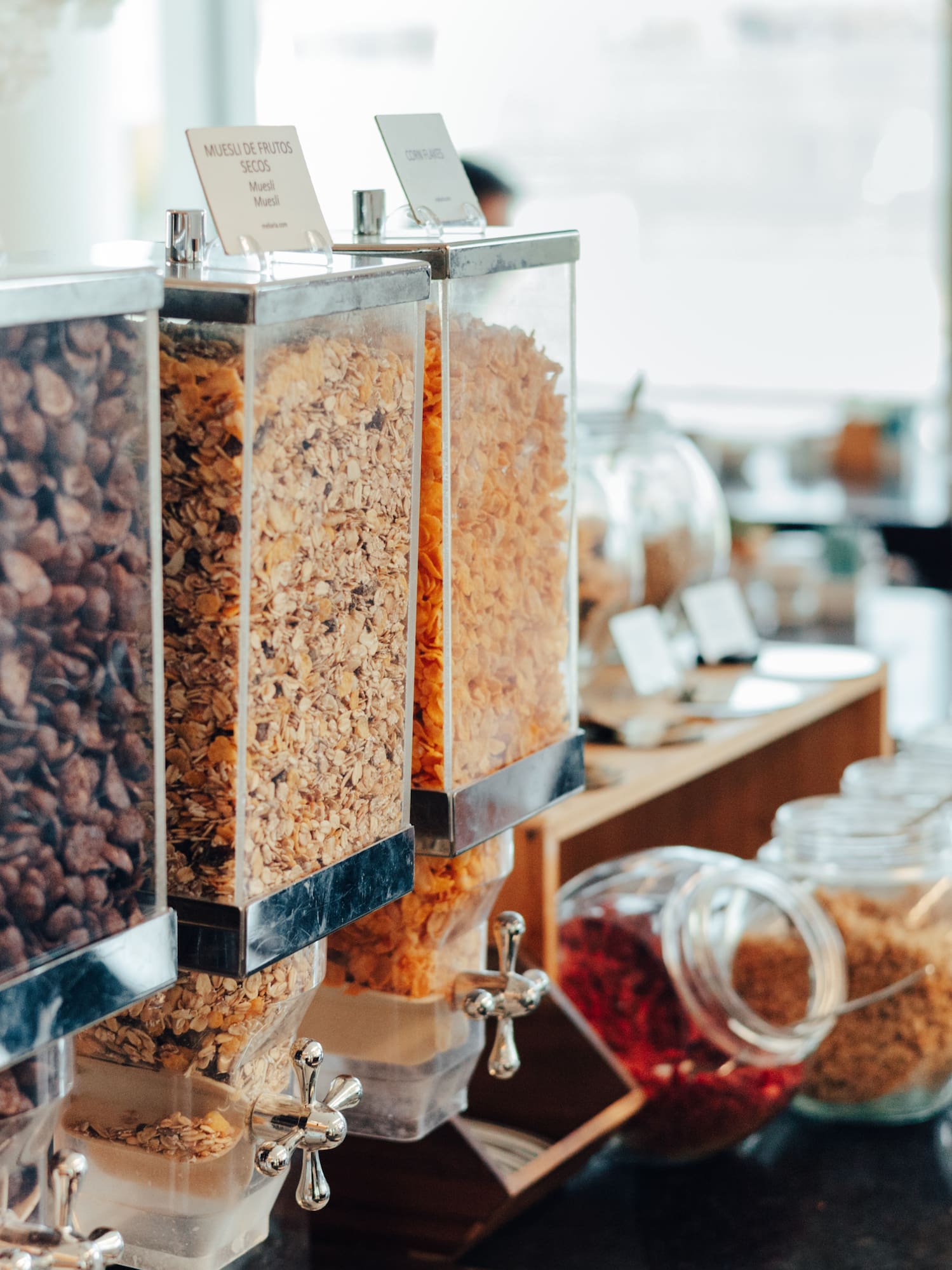 Breakfast buffet with chocolate, muesli, and cornflake cereal dispensers.