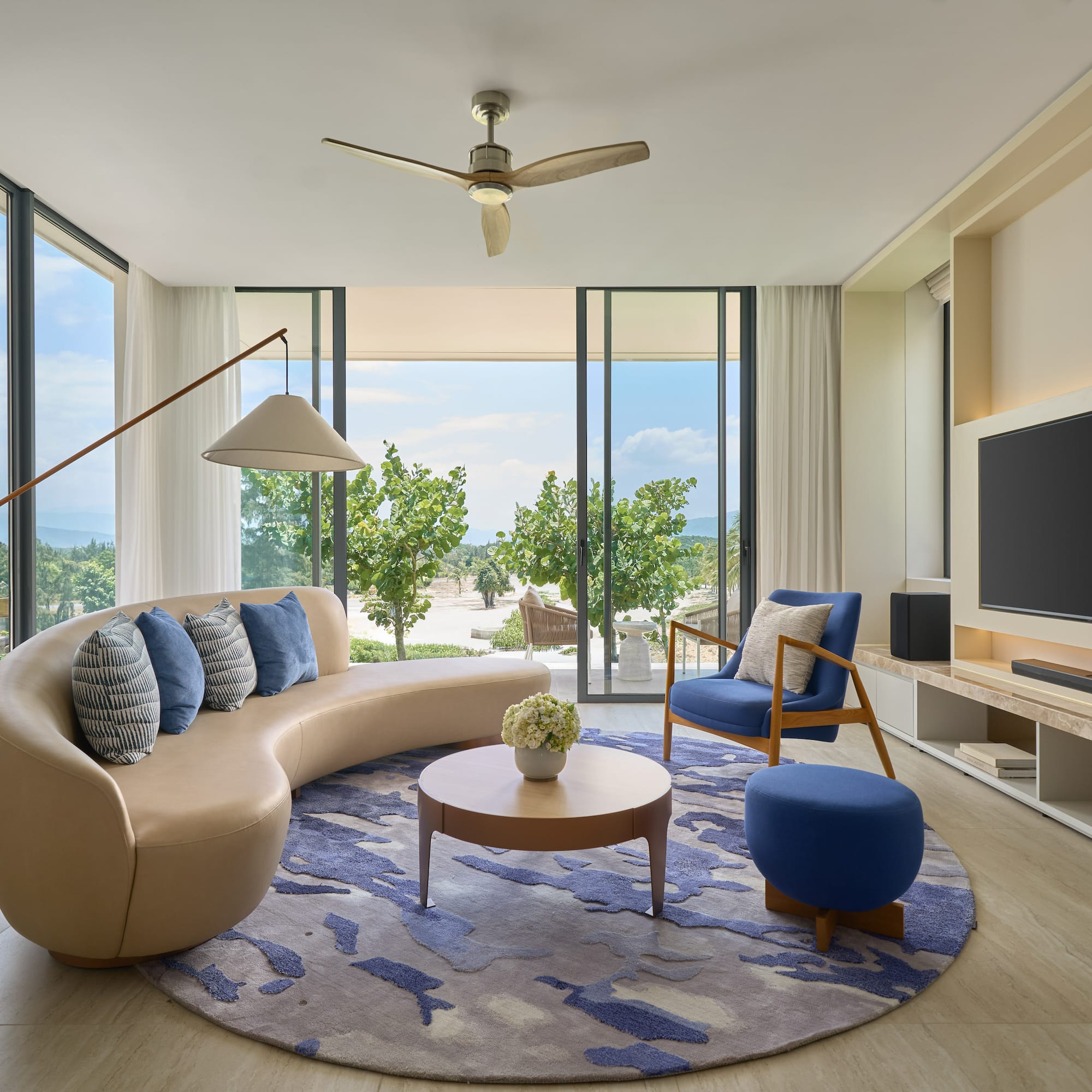Modern luxury living room with tropical ocean view and curved sofa.