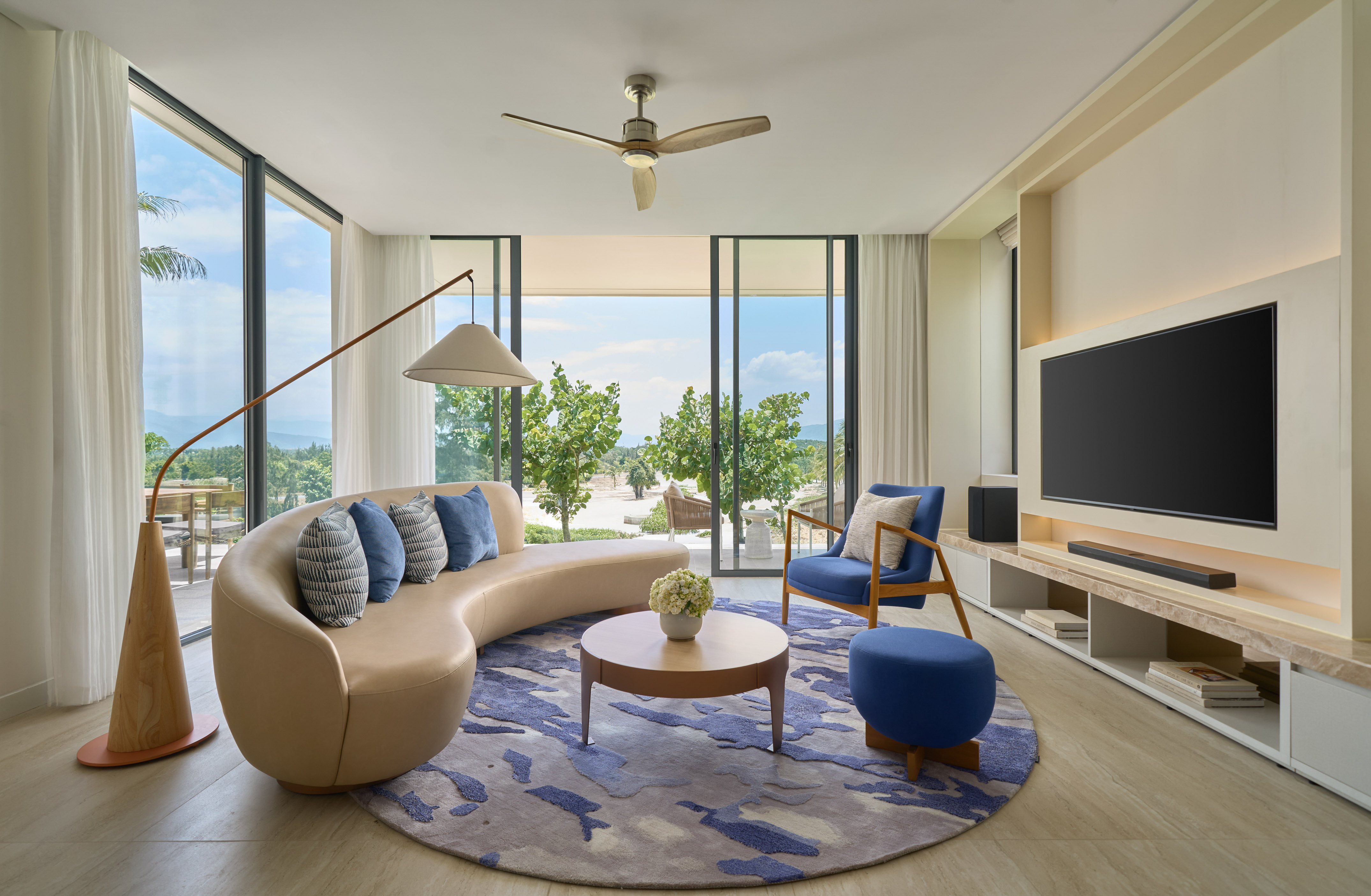 Modern luxury living room with tropical ocean view and curved sofa.