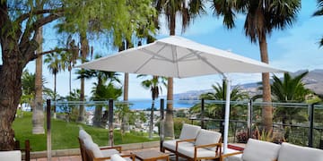a patio with white chairs and umbrella