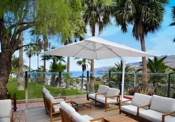 a patio with white chairs and umbrella