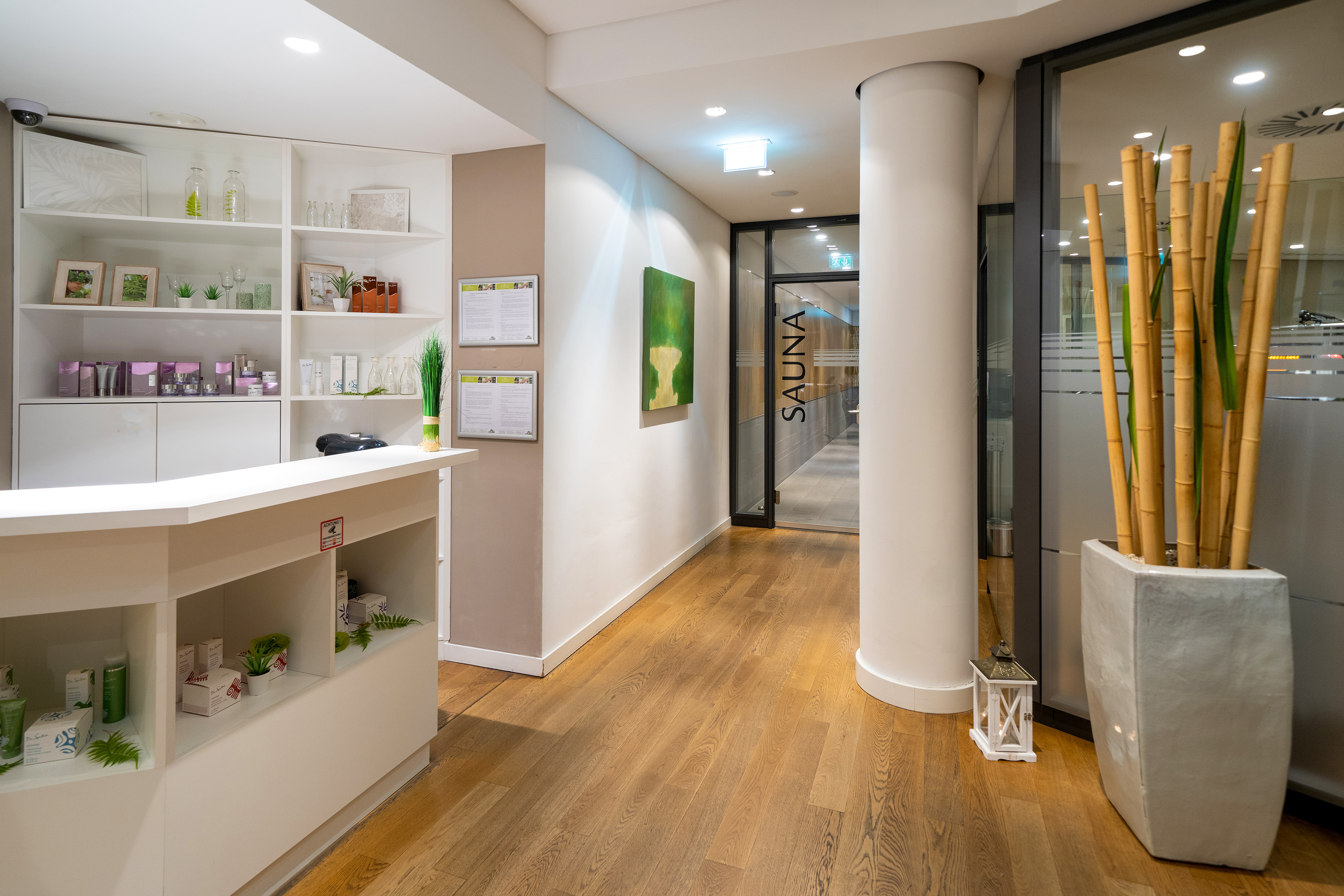 Modern spa reception with beauty products, bamboo, and sauna entrance.