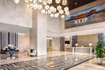 a lobby with a large chandelier and a large picture from the ceiling