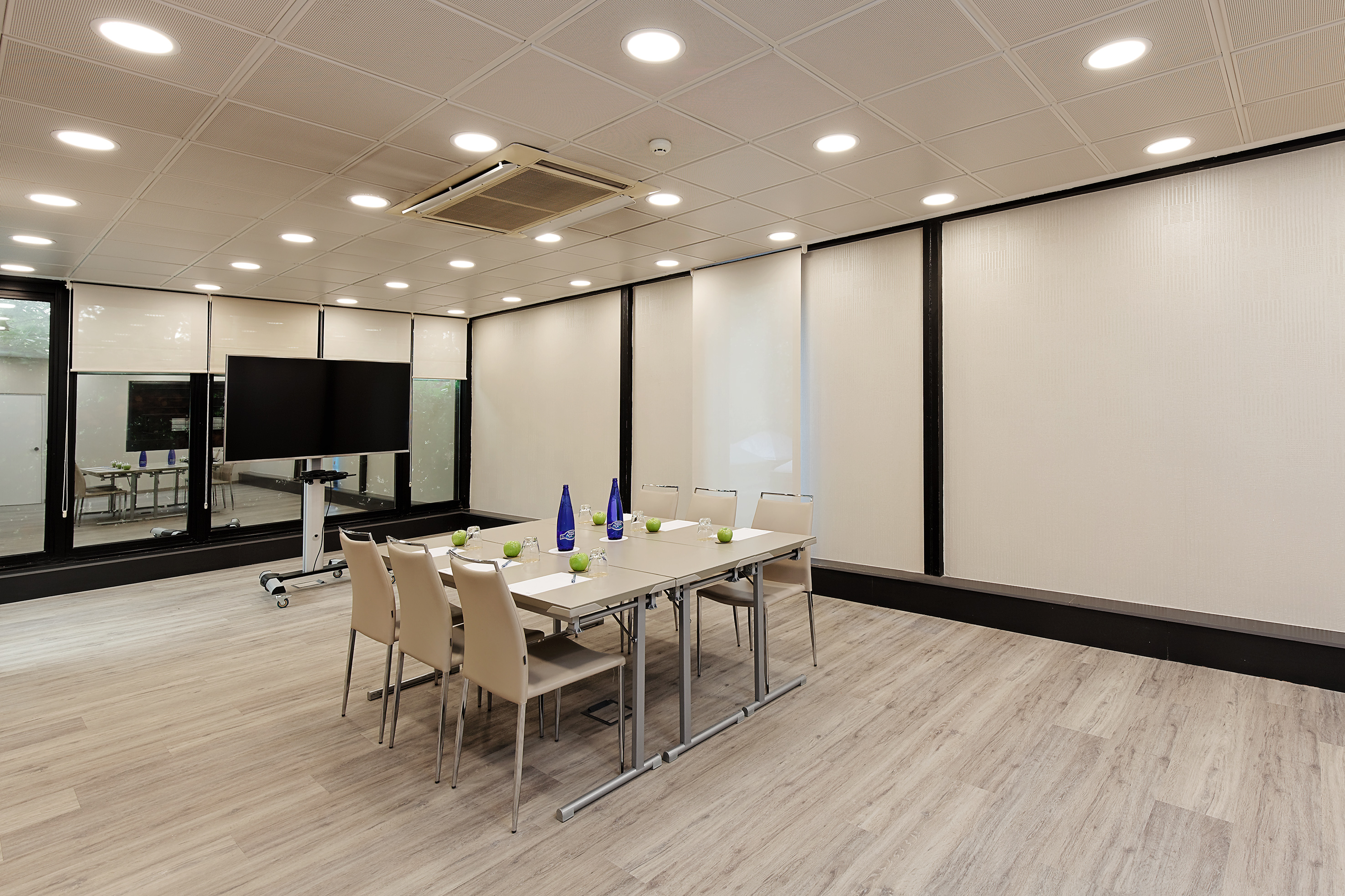 Modern meeting room with large table, chairs, TV, and light wood floor.
