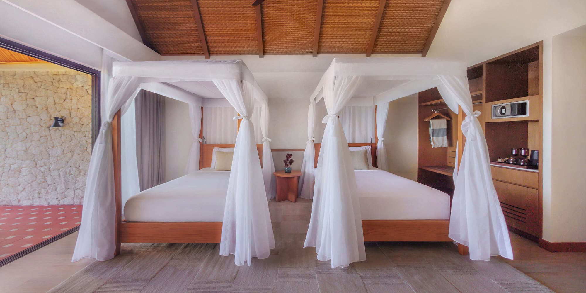 Luxury tropical bedroom with two canopy beds, bamboo ceiling, and patio.