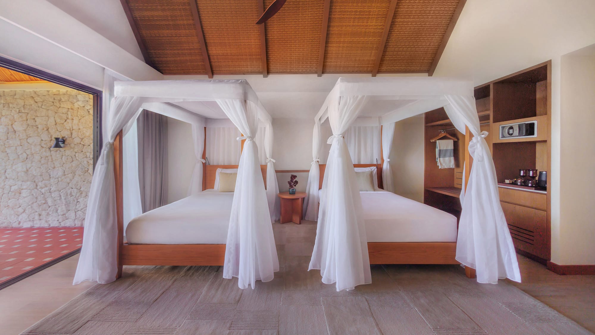 Luxury tropical bedroom with two canopy beds, bamboo ceiling, and patio.