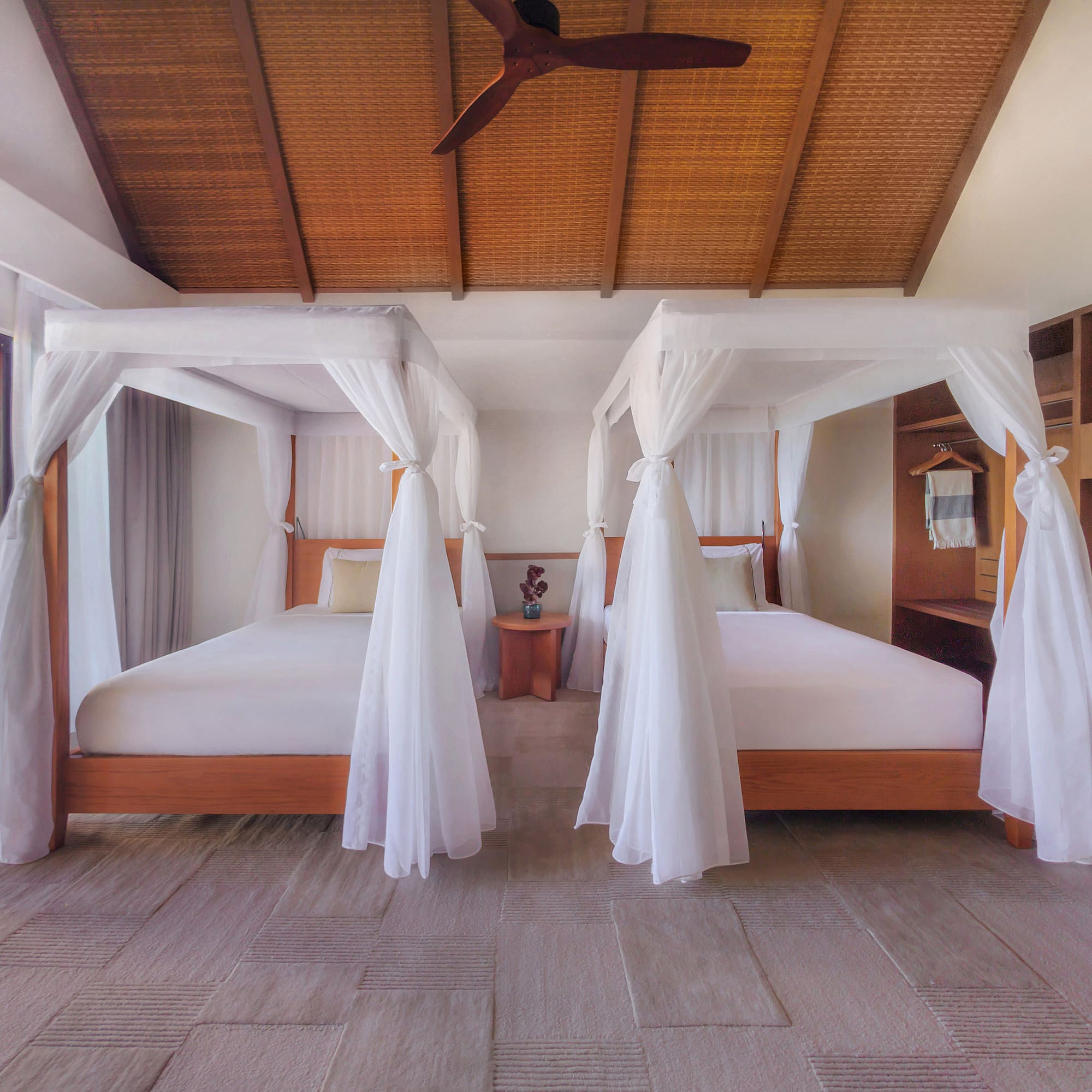 Luxury tropical bedroom with two canopy beds, bamboo ceiling, and patio.