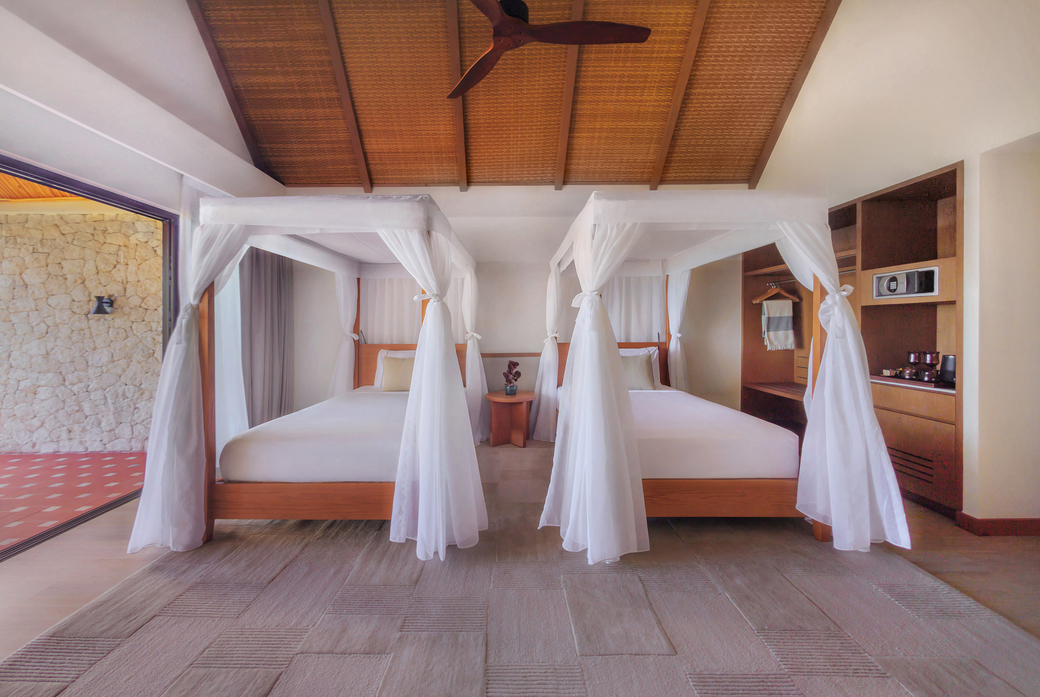 Luxury tropical bedroom with two canopy beds, bamboo ceiling, and patio.