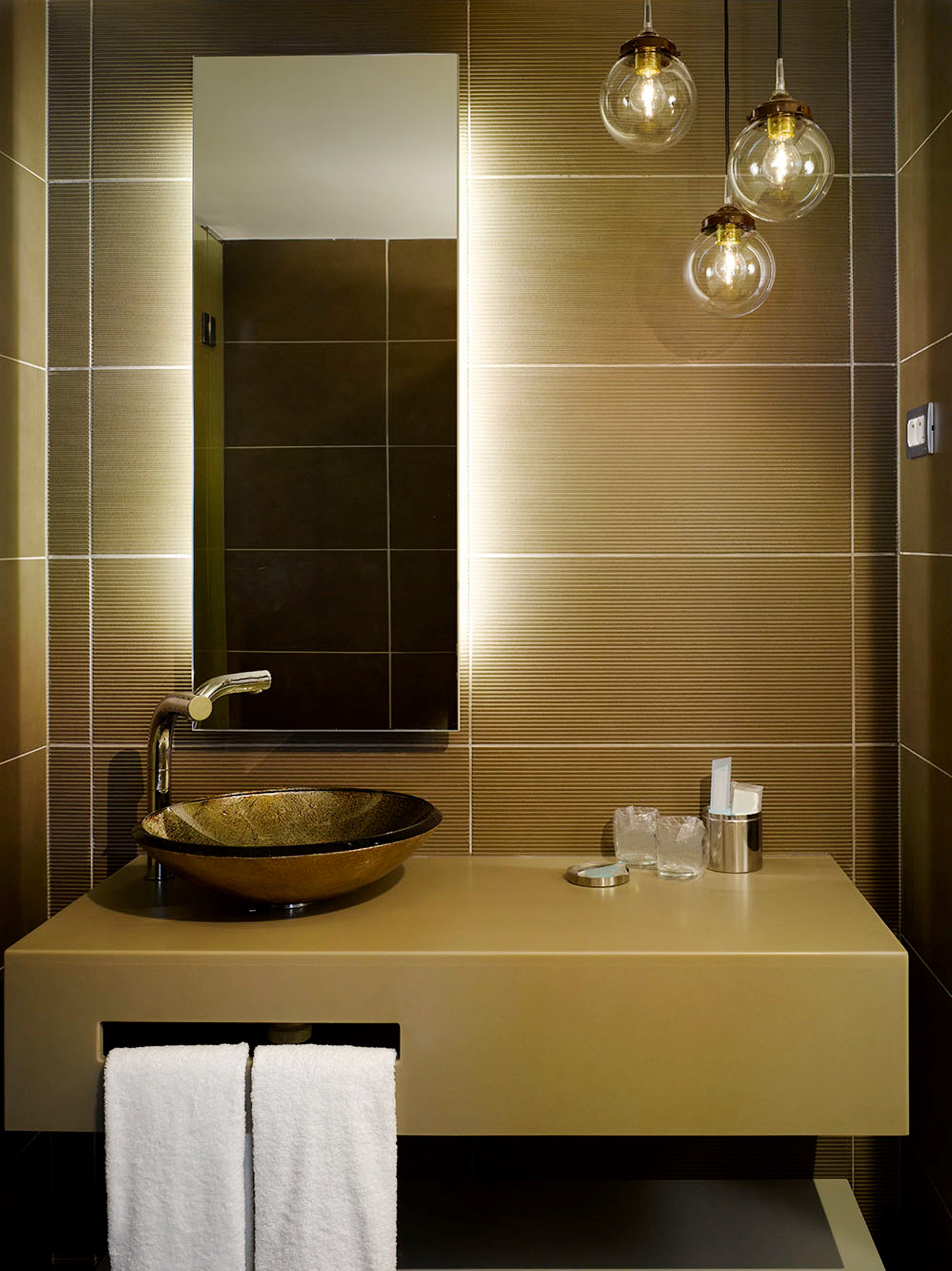 Modern bathroom with floating vanity, golden basin, brown tiles, and pendant lights.