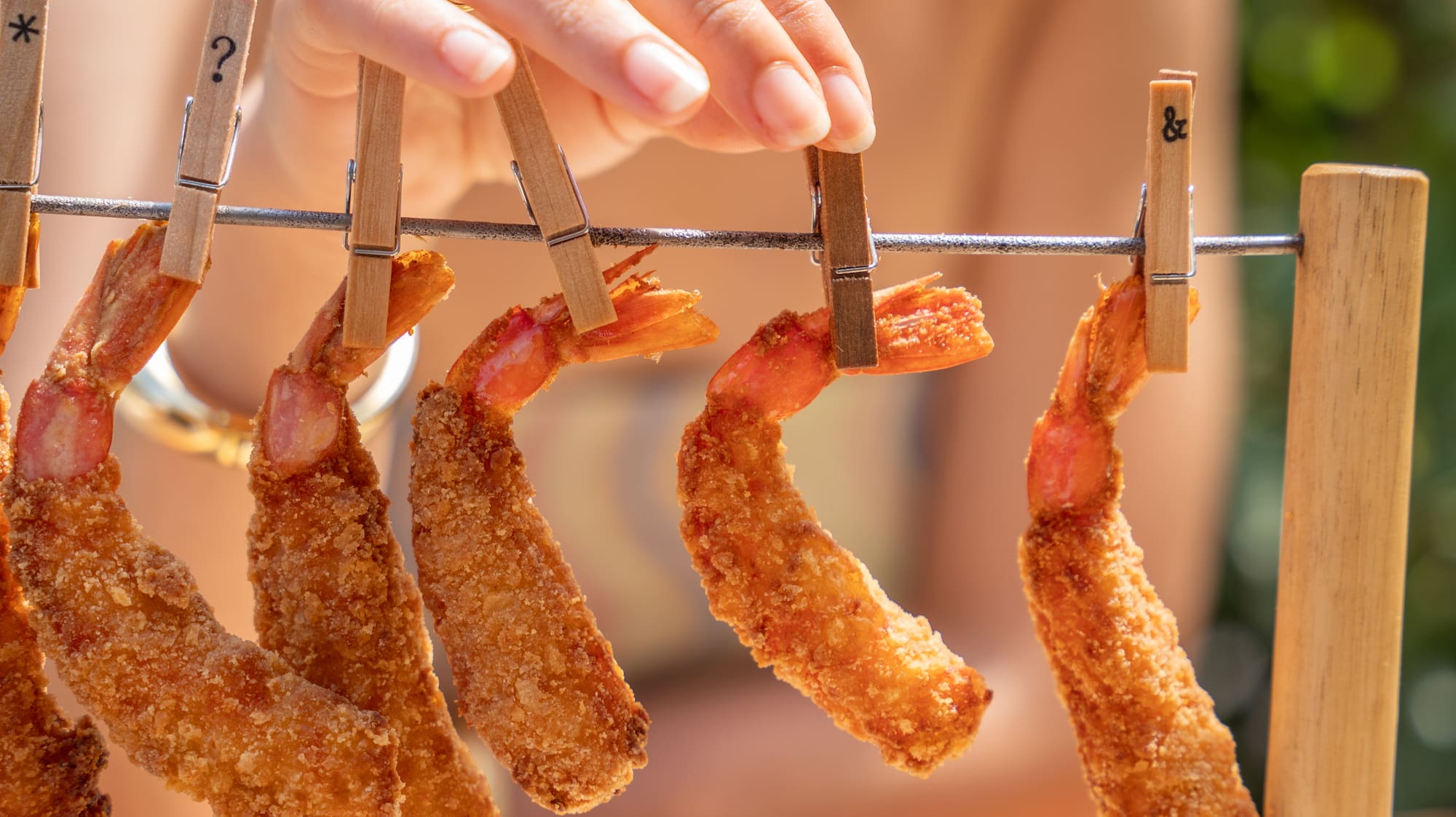 a hand holding a line of fried shrimp