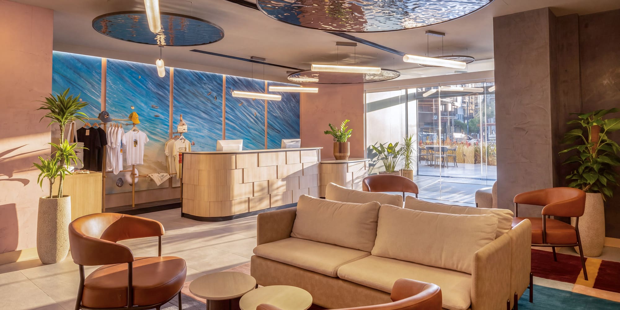 Hotel lobby with modern reception, lounge seating, and ocean wave mural backdrop.