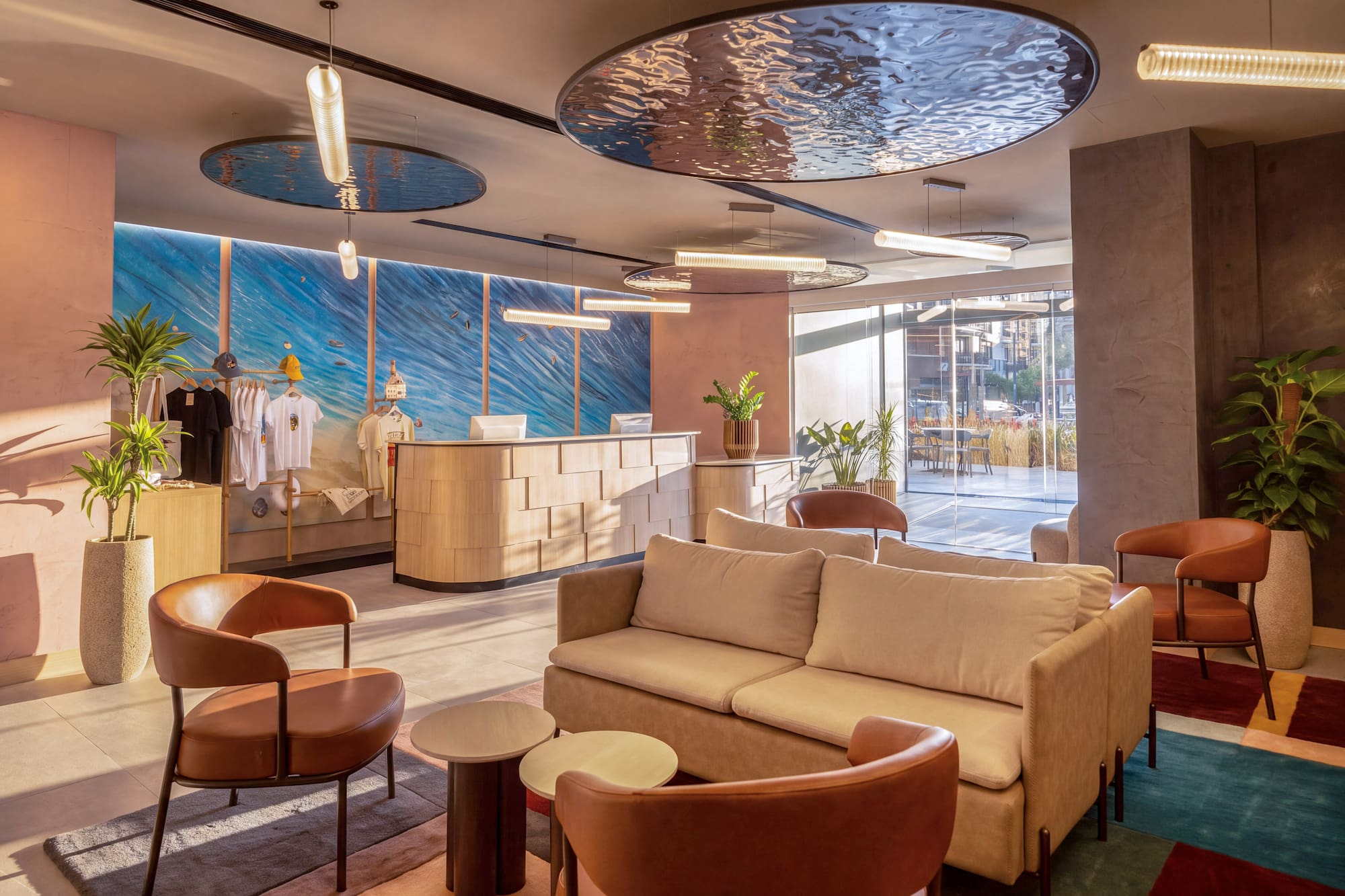 Hotel lobby with modern reception, lounge seating, and ocean wave mural backdrop.