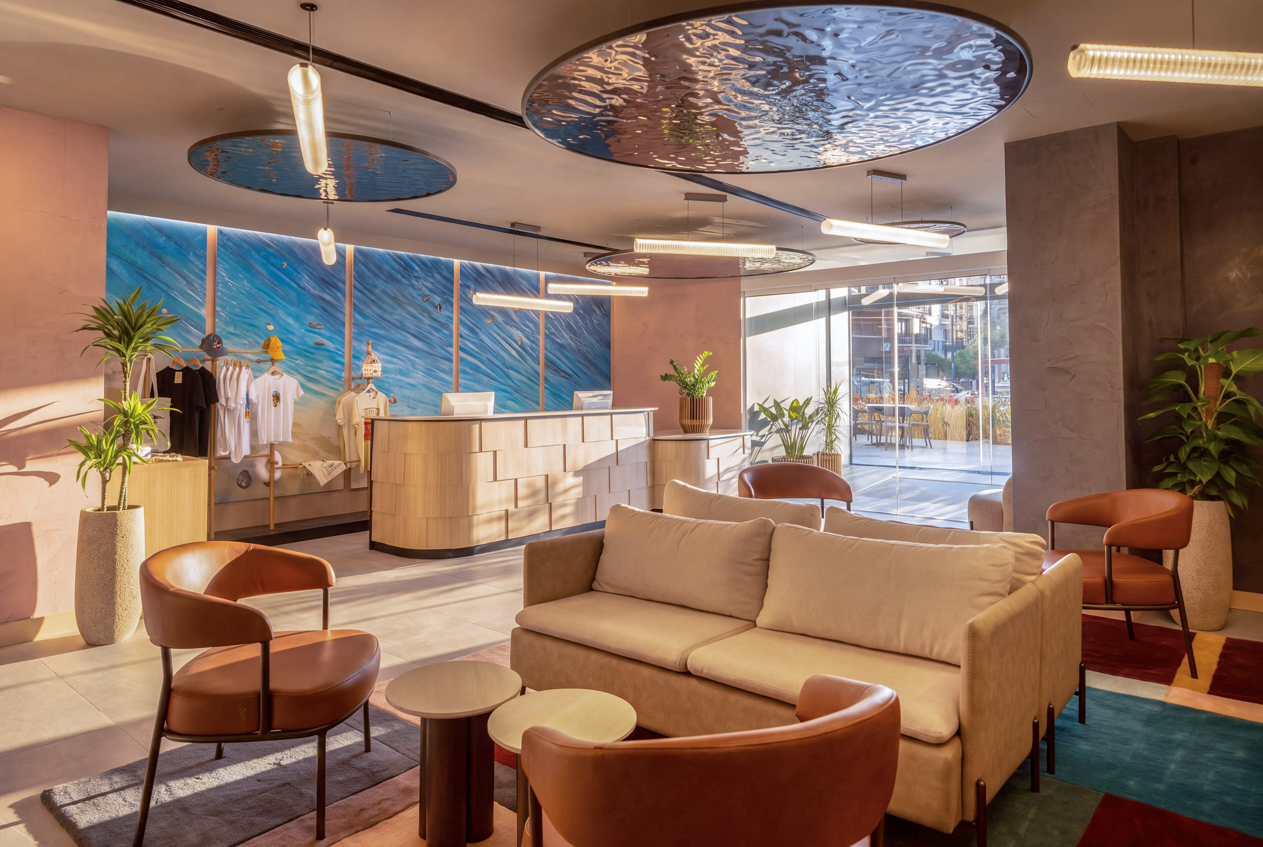 Hotel lobby with modern reception, lounge seating, and ocean wave mural backdrop.