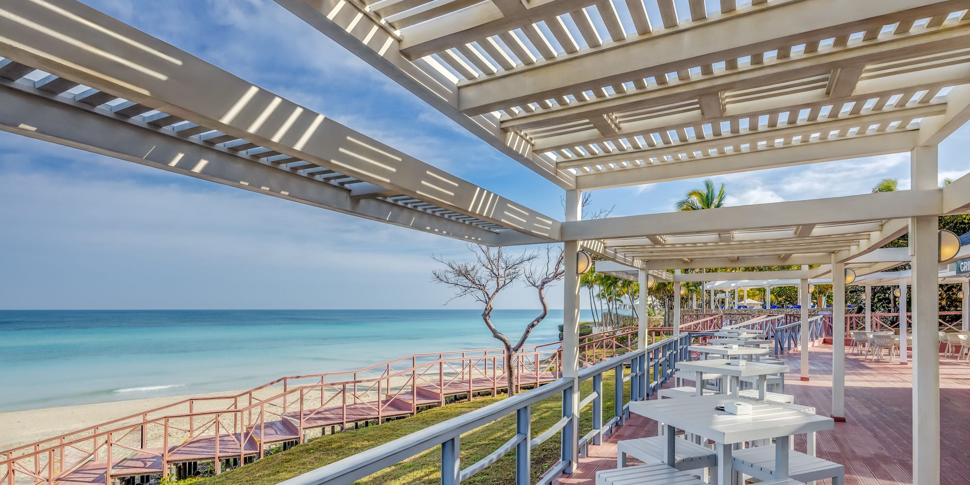 a white tables and chairs on a deck overlooking a body of water