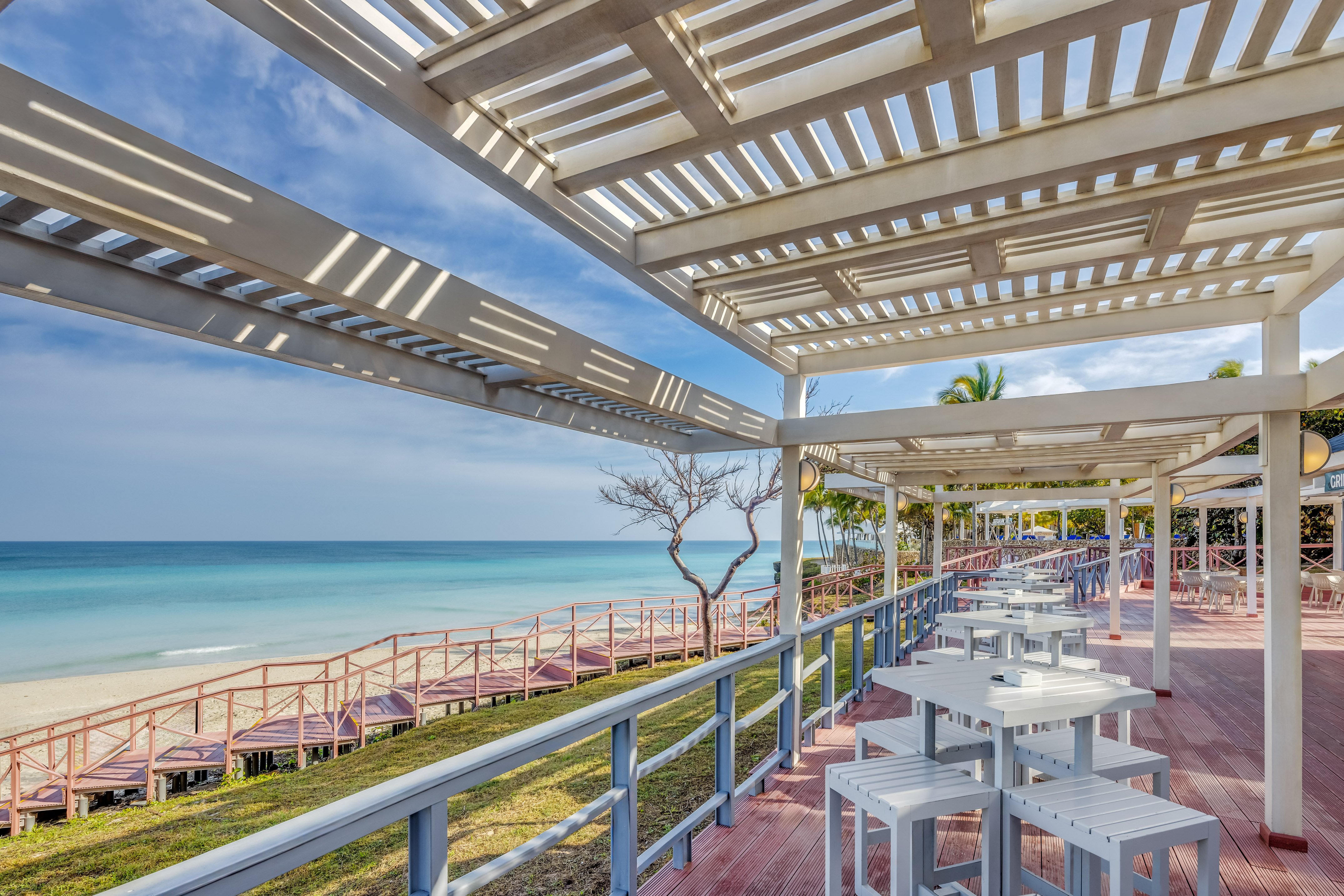 a white tables and chairs on a deck overlooking a body of water