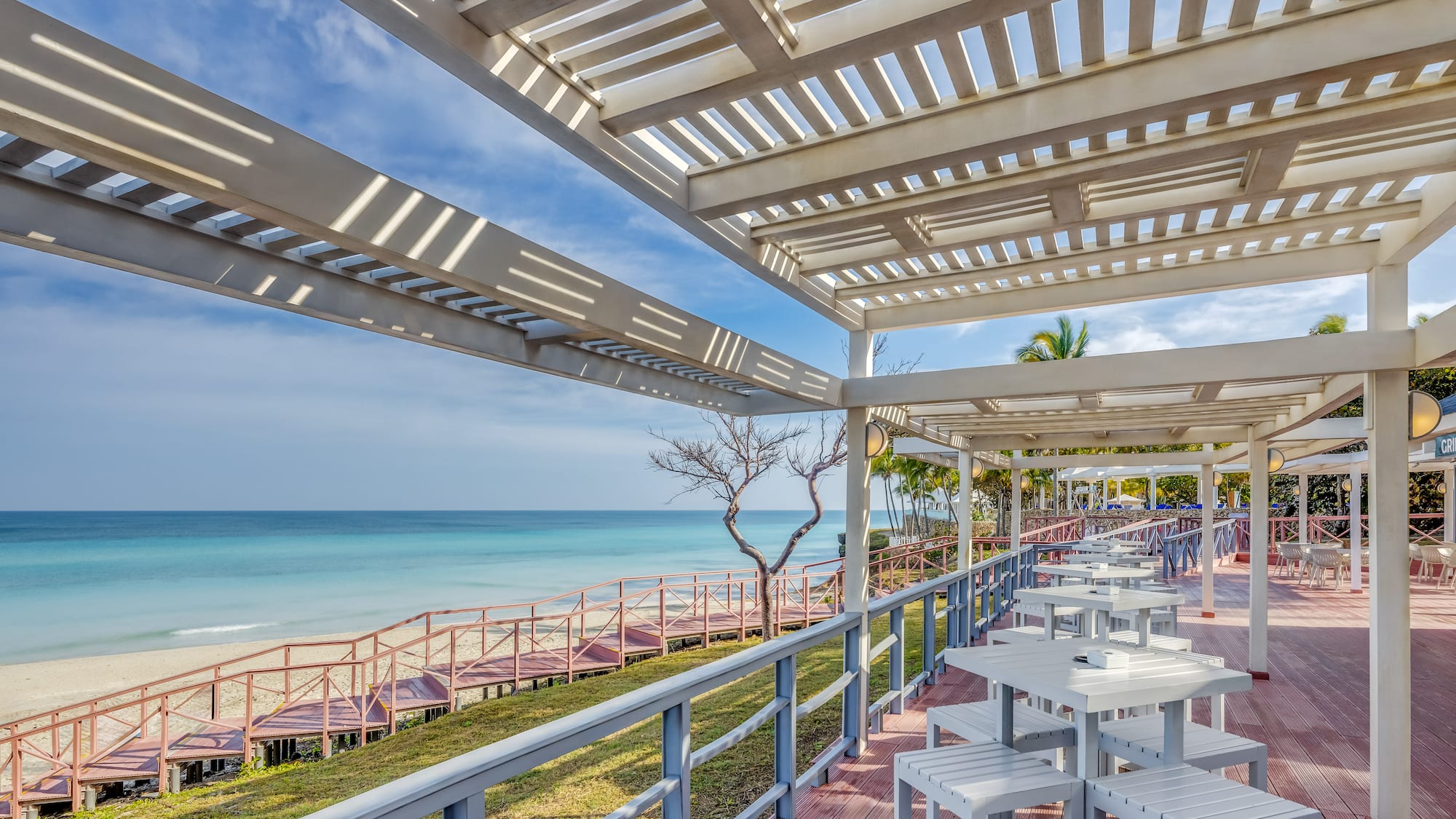 a white tables and chairs on a deck overlooking a body of water