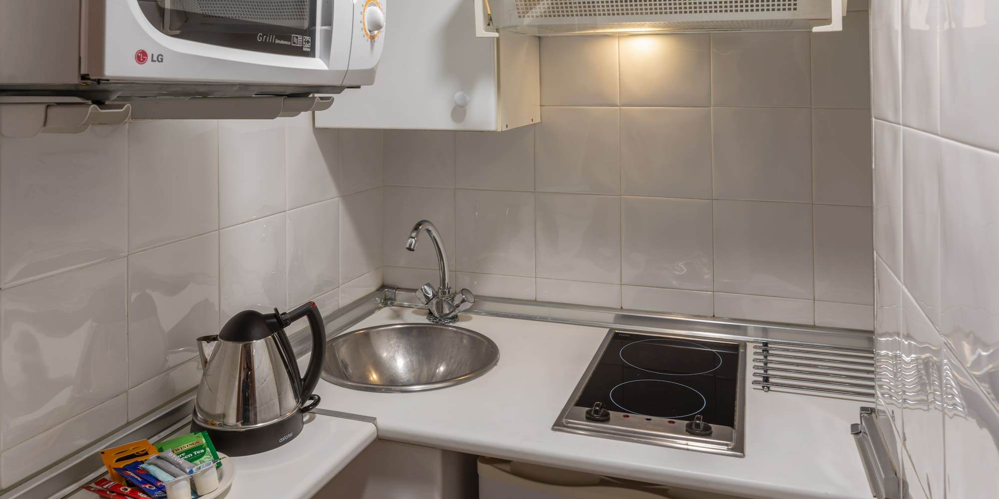 Studio kitchenette with microwave, sink, electric hob, kettle, tea.