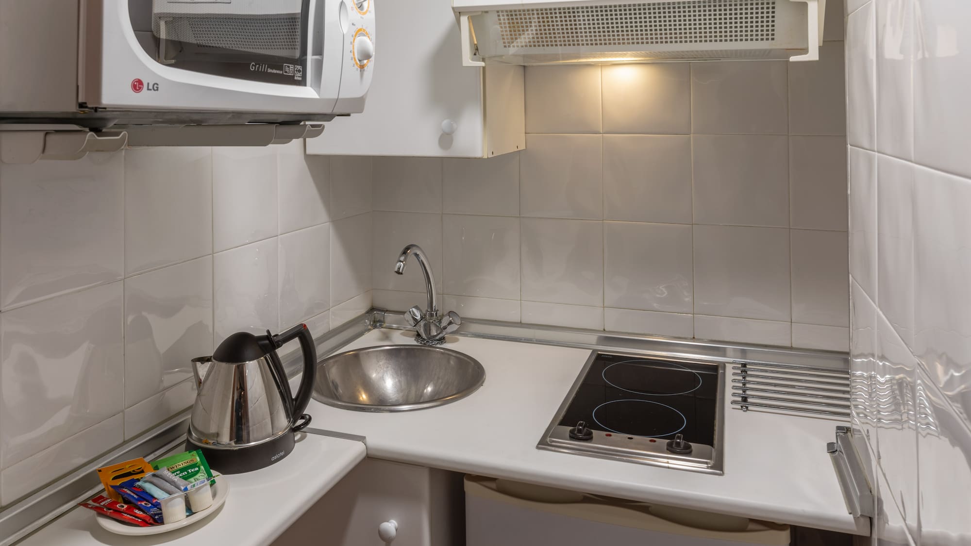 Studio kitchenette with microwave, sink, electric hob, kettle, tea.