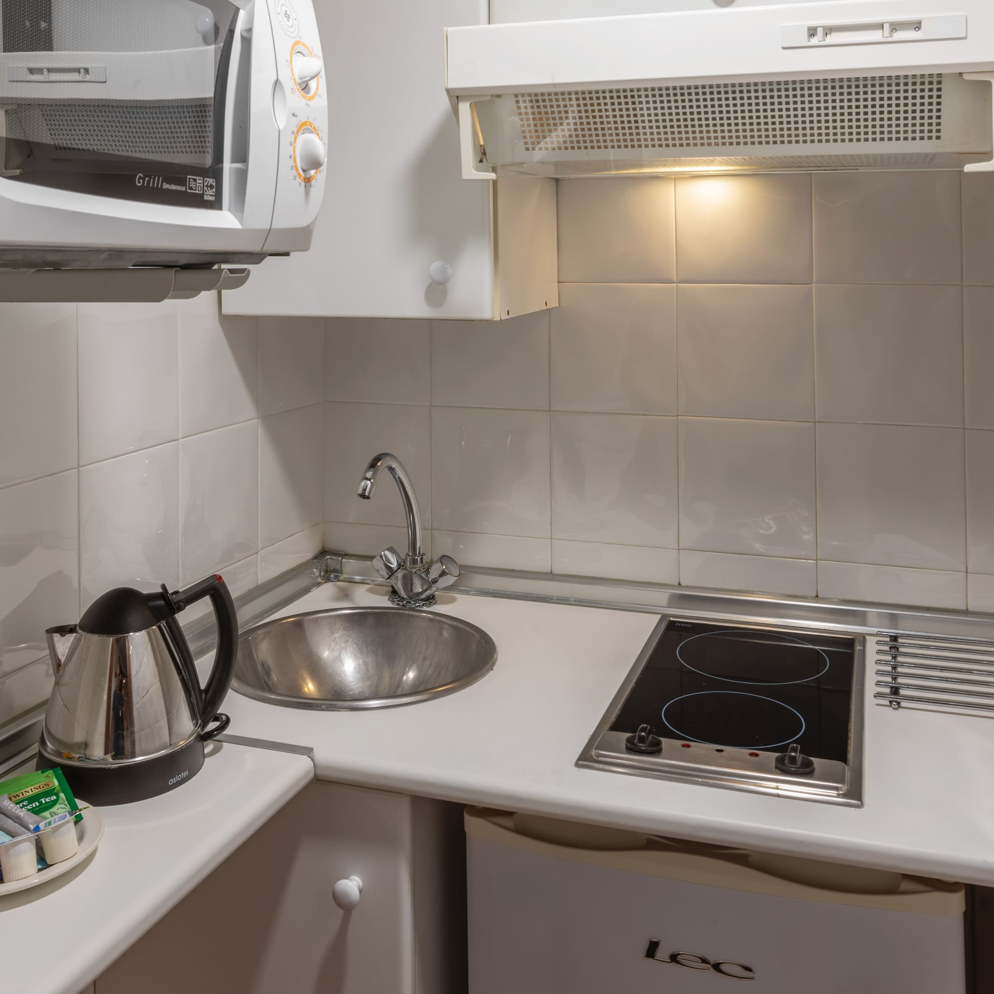 Studio kitchenette with microwave, sink, electric hob, kettle, tea.