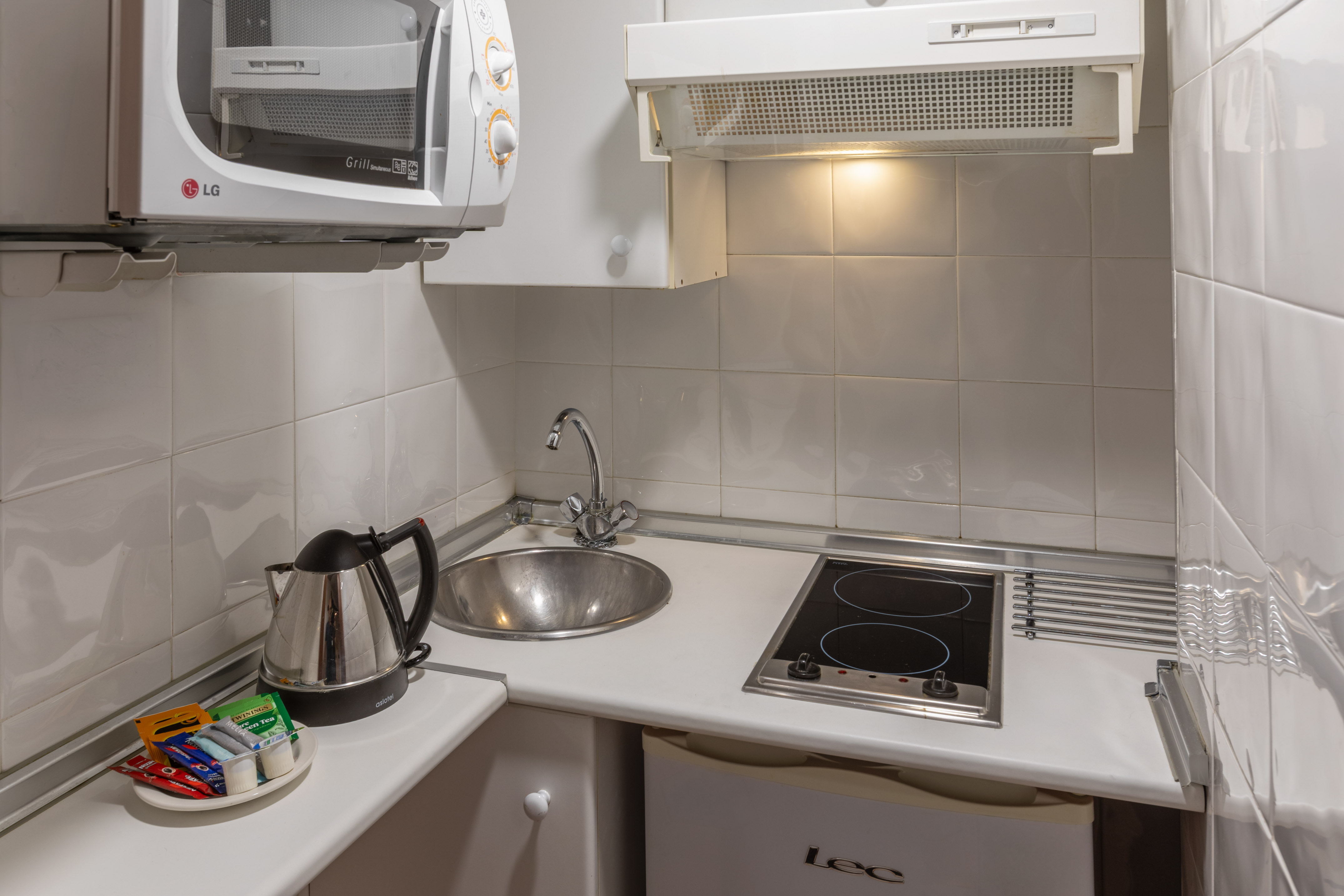 Studio kitchenette with microwave, sink, electric hob, kettle, tea.