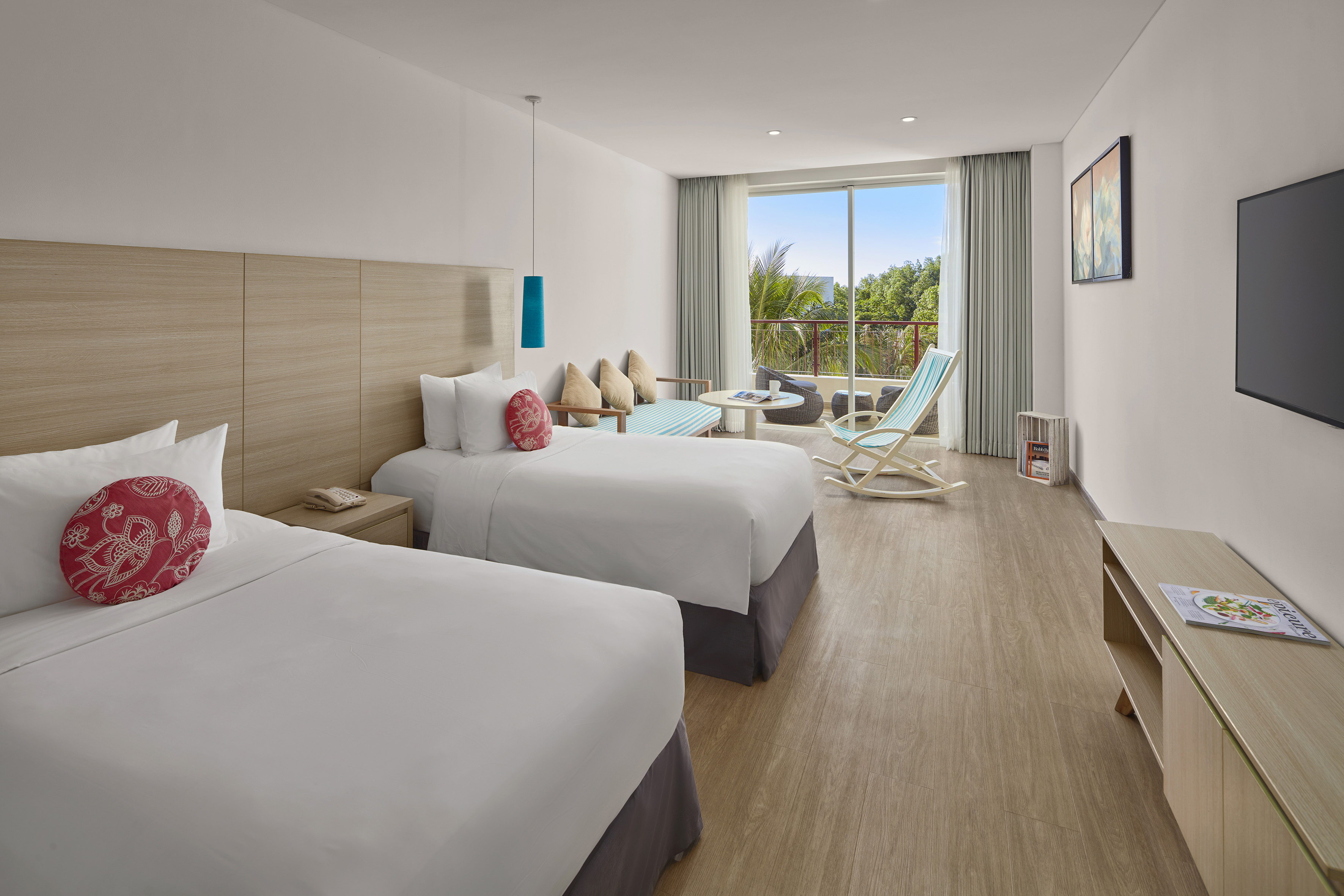 Modern hotel room with twin beds, balcony, and tropical view.