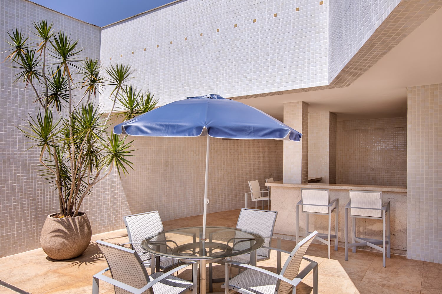 a patio with a table and chairs and a blue umbrella