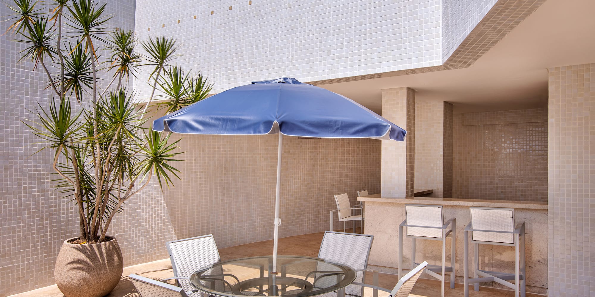 a patio with a table and chairs and a blue umbrella