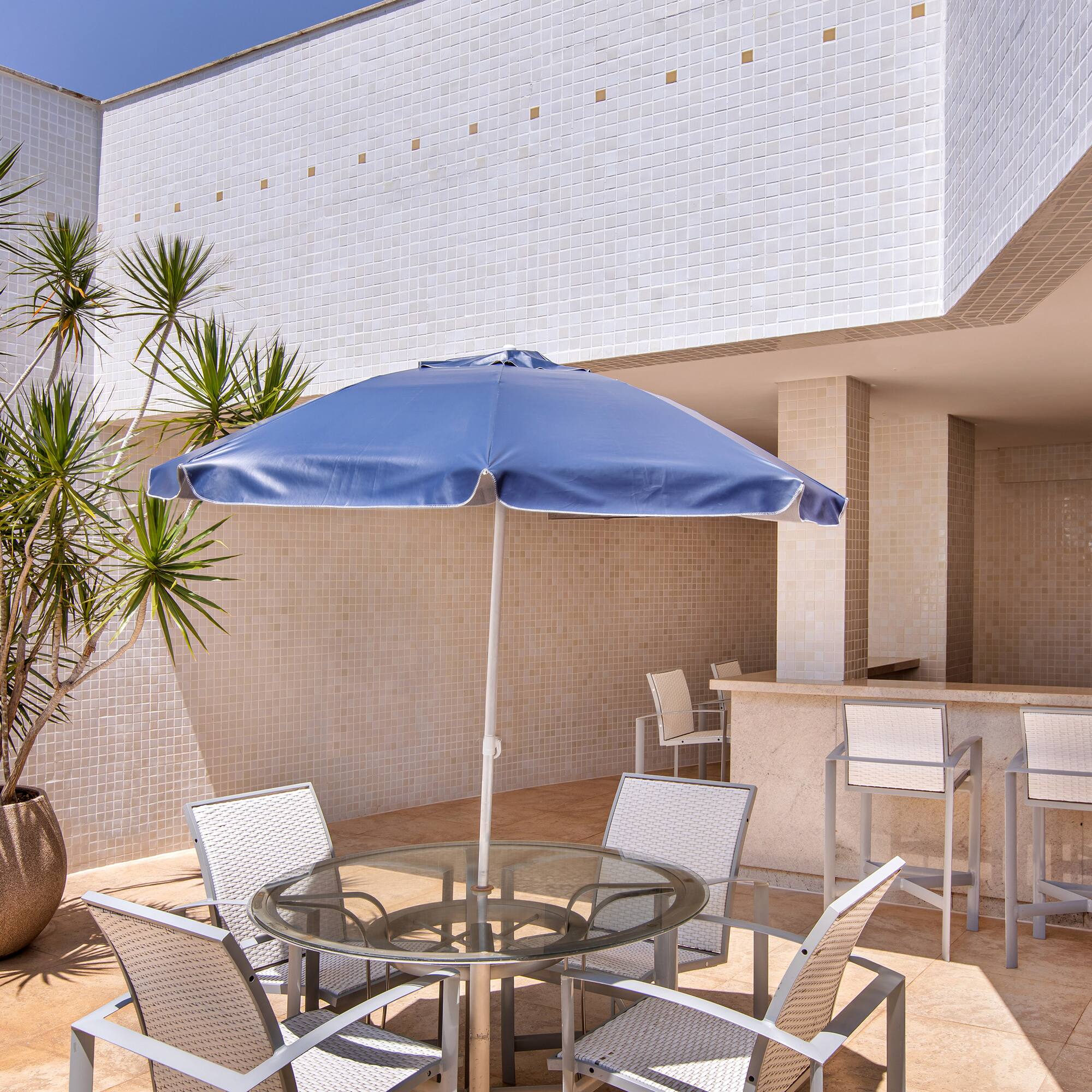 a patio with a table and chairs and a blue umbrella