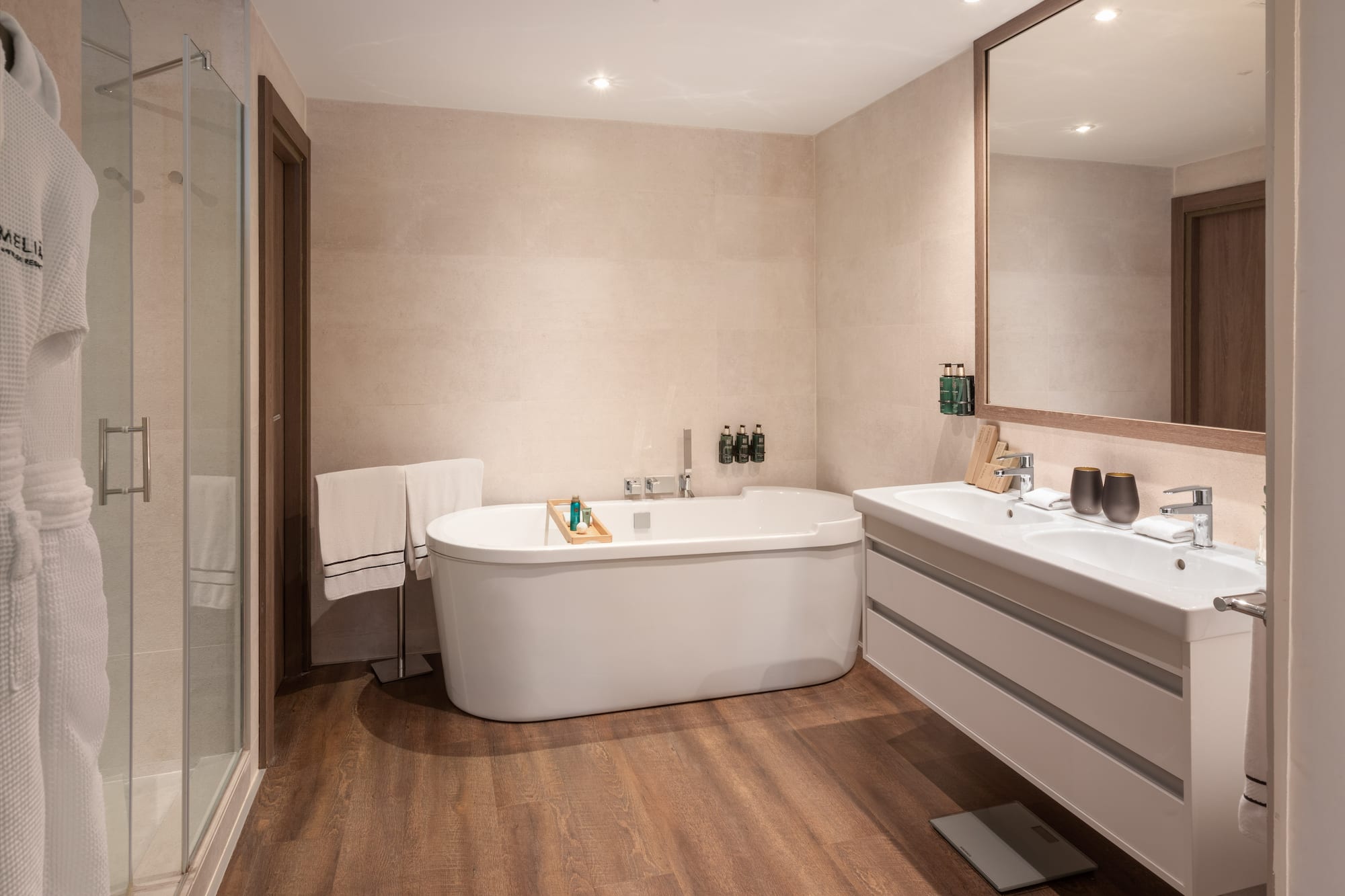 Luxury hotel bathroom with white tub, glass shower, and dual vanity.