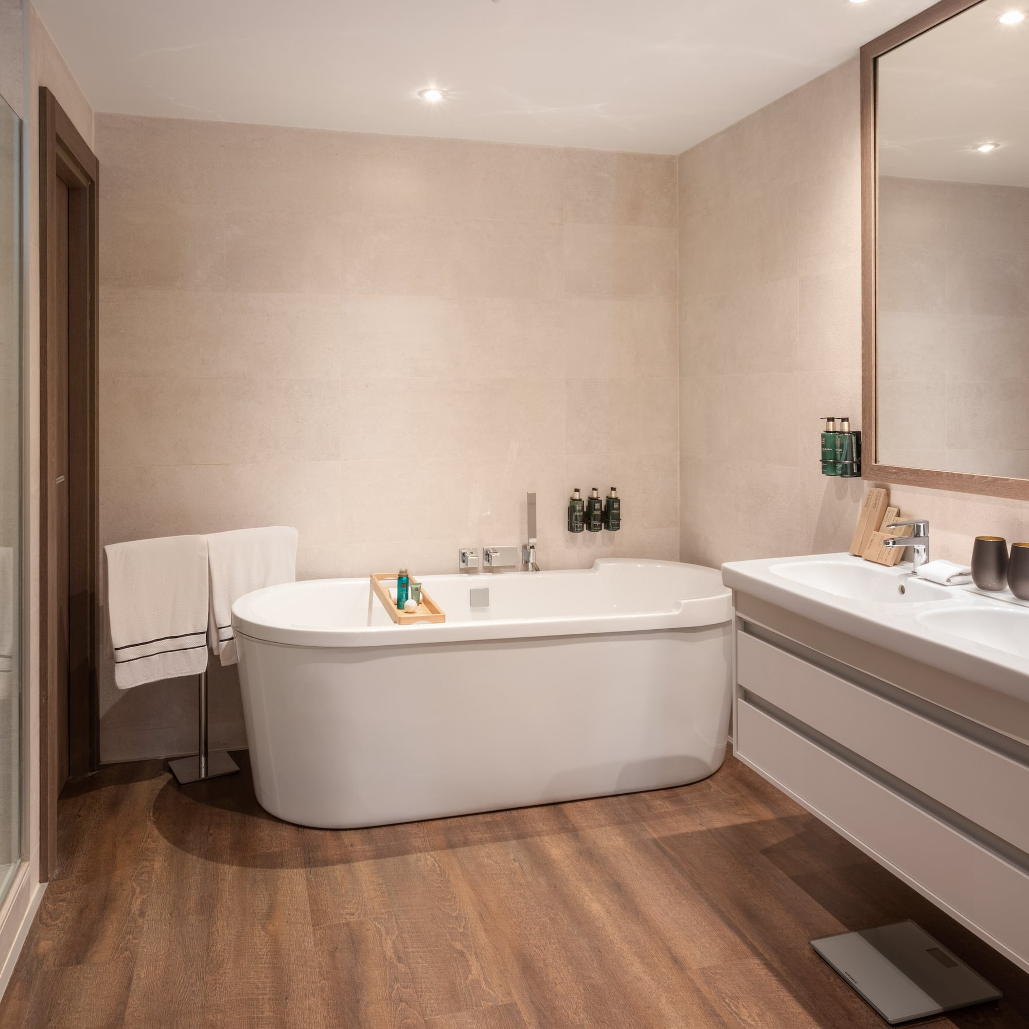Luxury hotel bathroom with white tub, glass shower, and dual vanity.