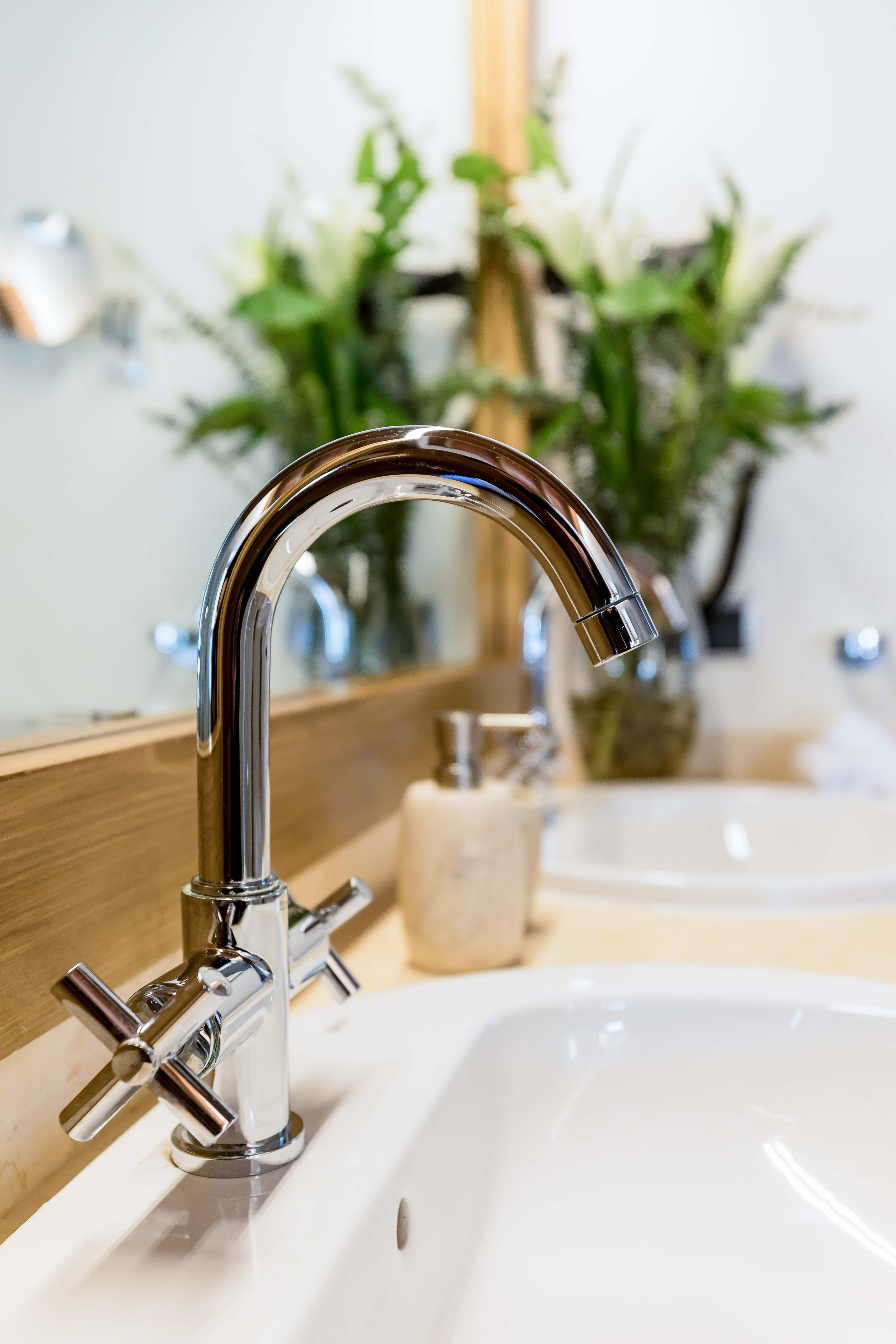 Modern chrome bathroom faucet with cross handles over a white sink.