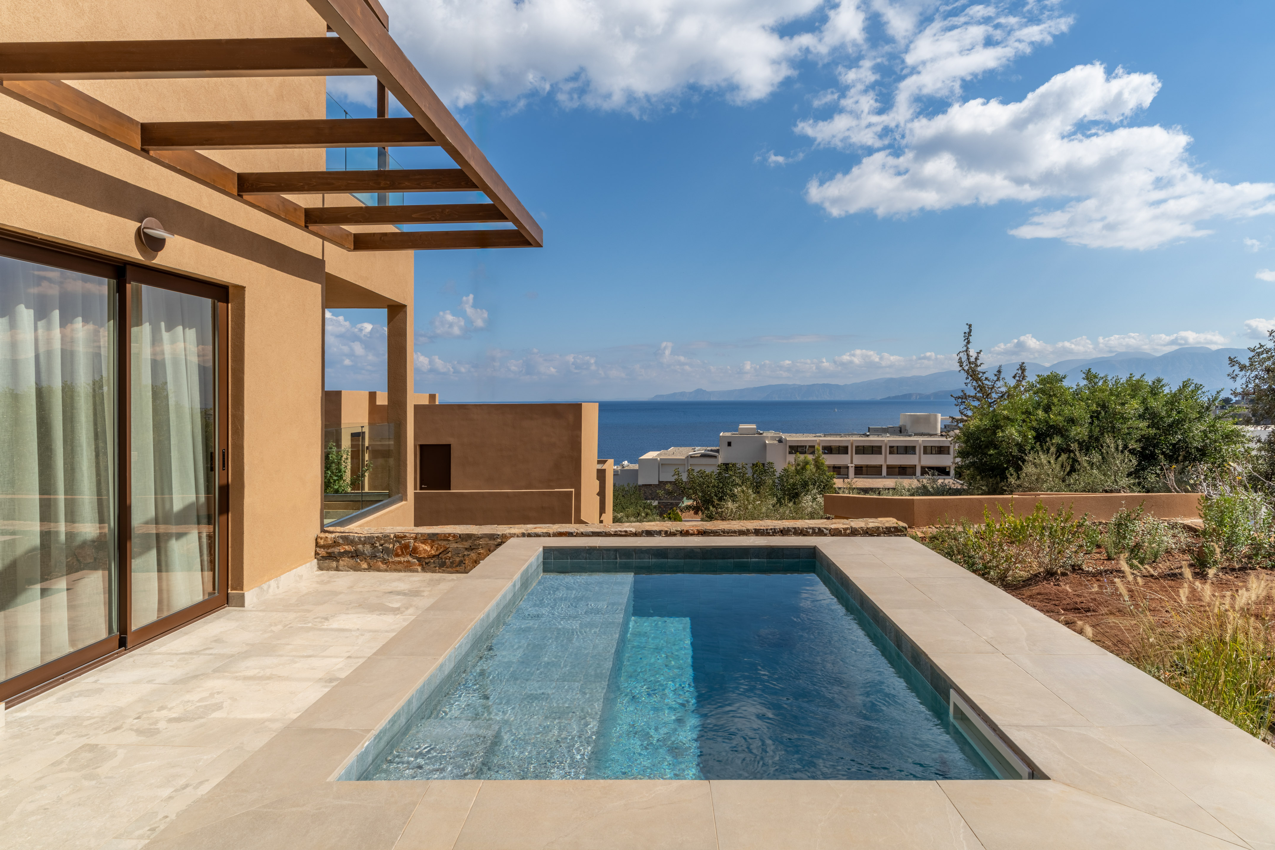Tan villa with private plunge pool, wooden pergola, and expansive ocean view.