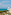 Hotel resort moderno con balcón al mar, palmeras y sombrillas.