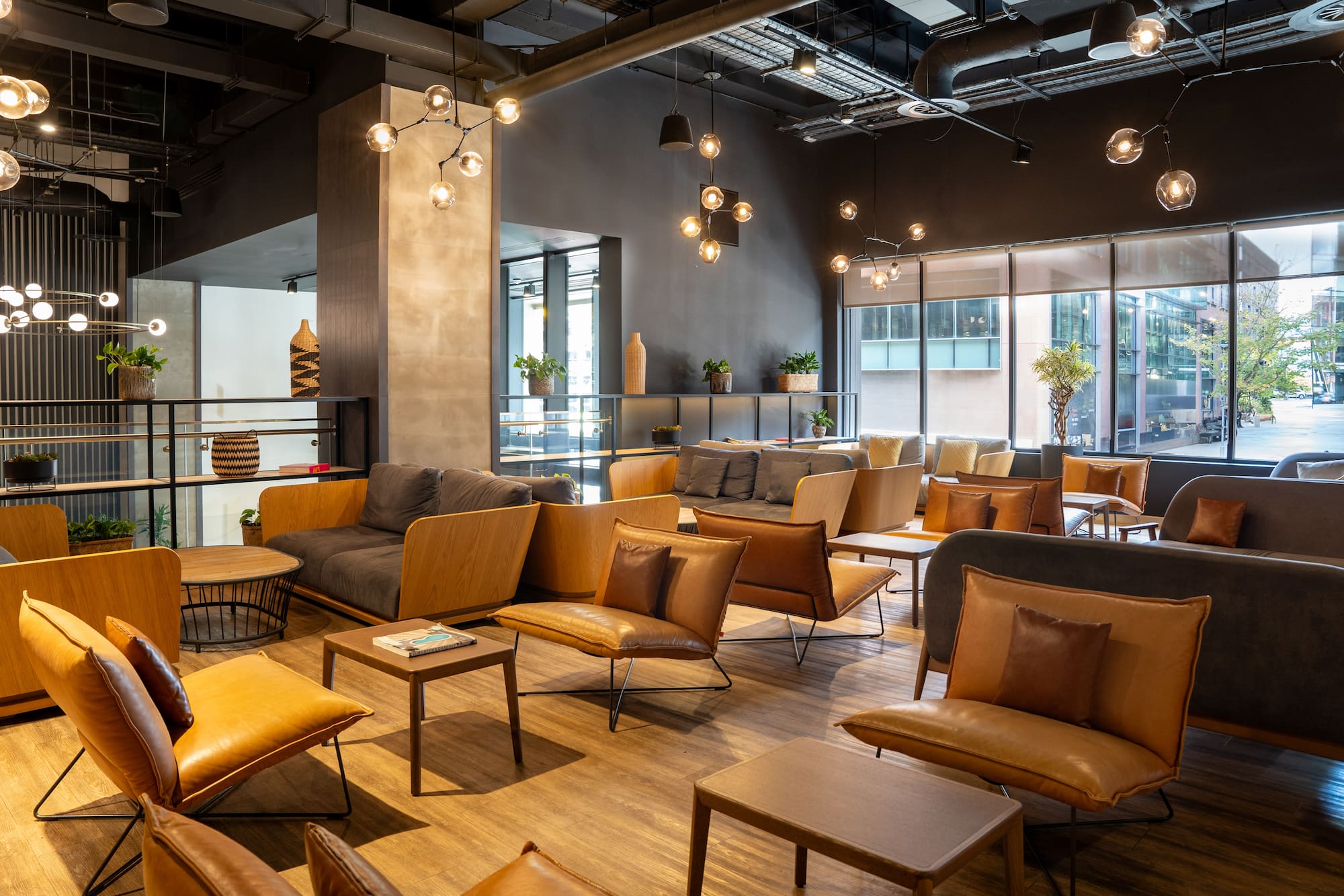 Modern lounge with stylish brown leather chairs, gray sofas, and globe lighting.