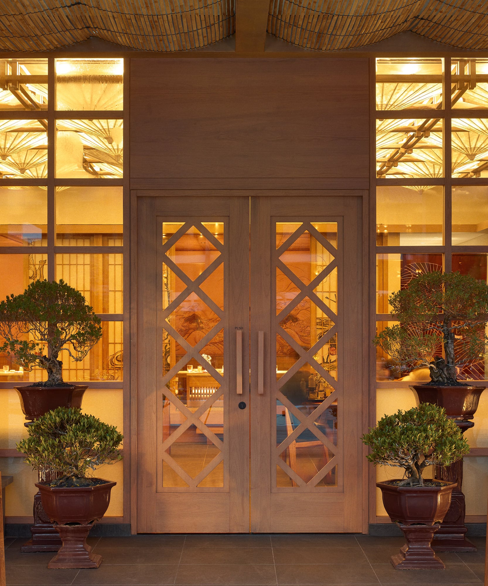 a front door of a building with a couple of potted trees