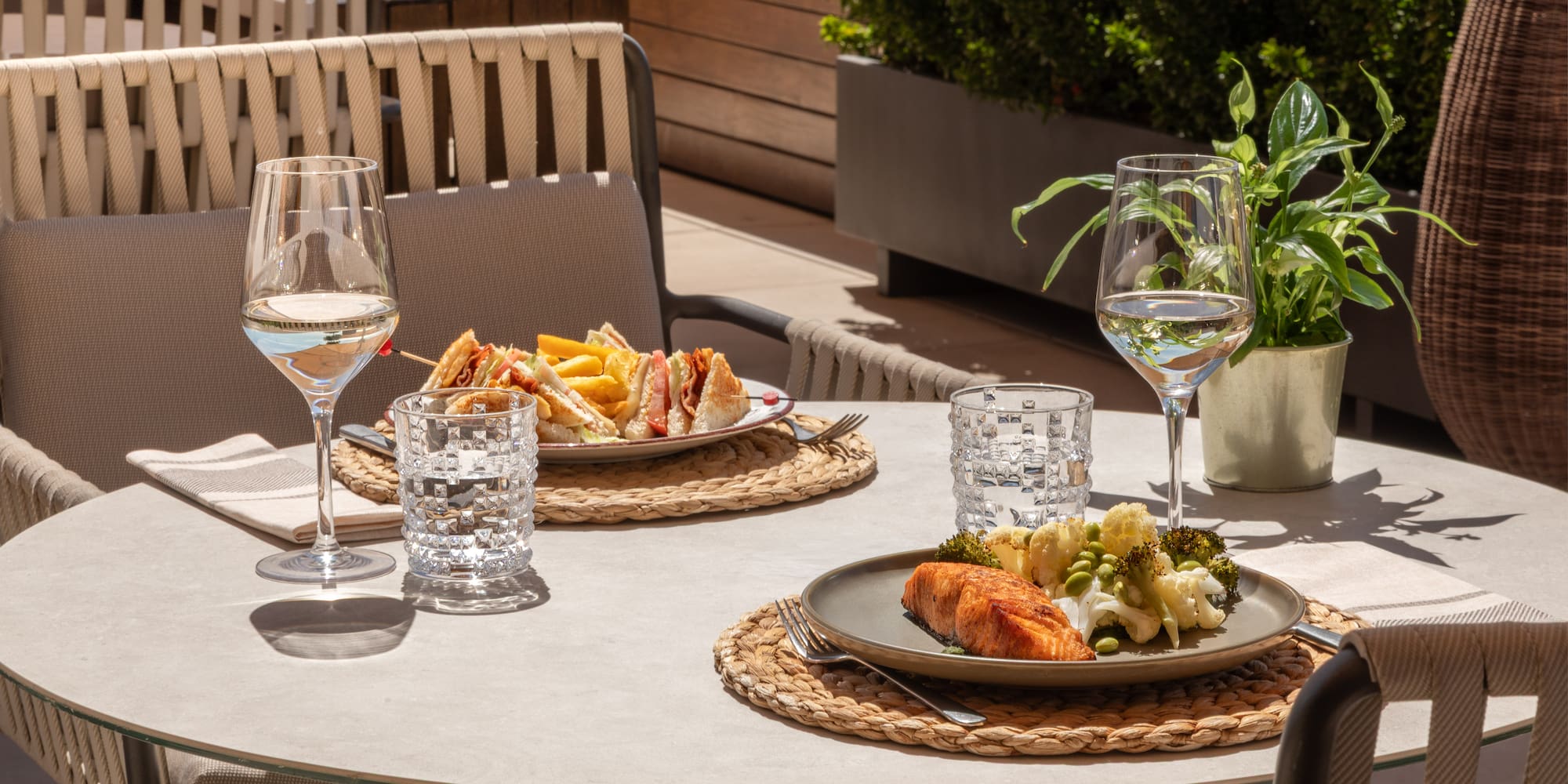 Outdoor dining: grilled salmon, club sandwich, white wine on a terrace.